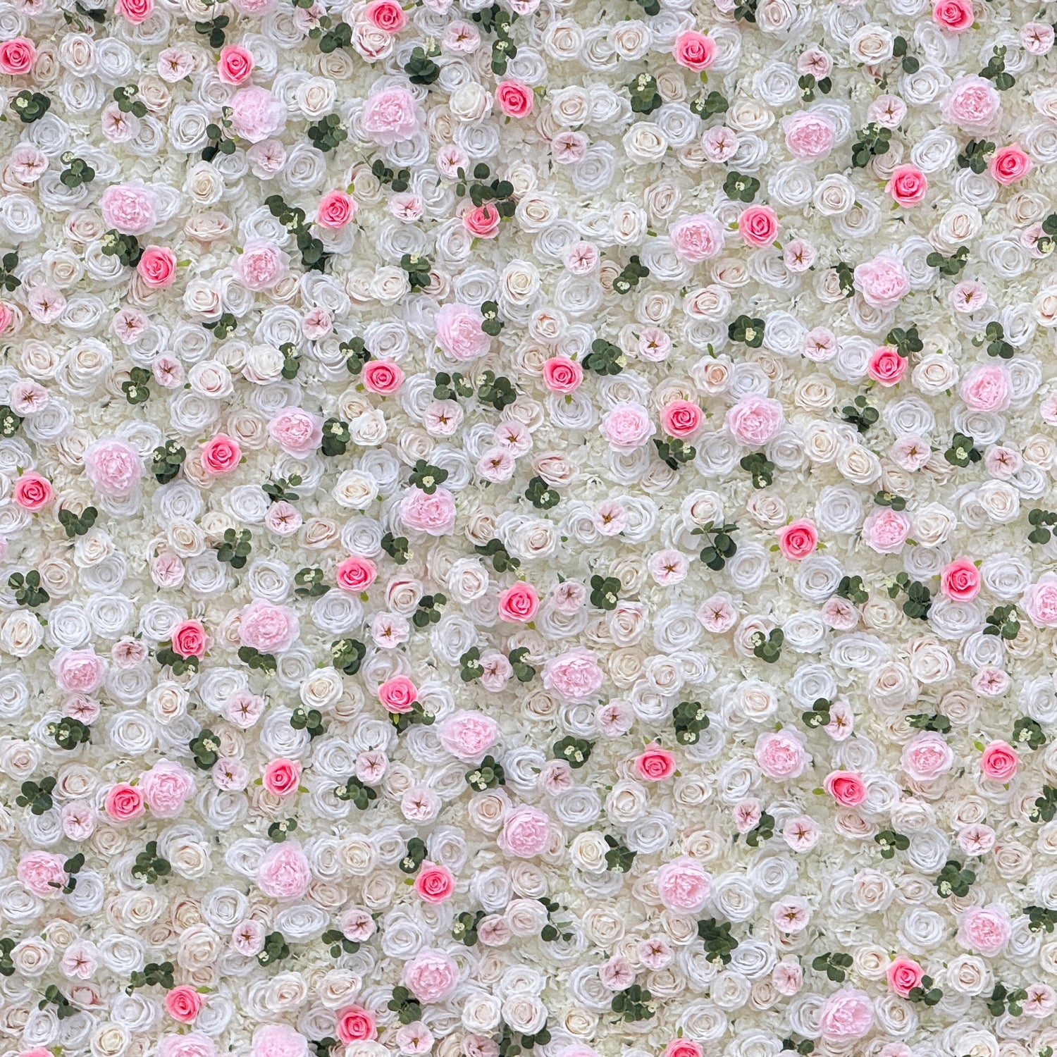 This photo showcases a stunning floral wall, likely by ValarFlowers, featuring artificial roses in soft pink and white hues, interspersed with greenery. The dense arrangement creates a romantic and elegant ambiance, perfect for weddings or other formal events. The realistic appearance of the faux flowers adds a touch of timeless beauty, making it an ideal backdrop for capturing memorable moments with a dreamy, celebratory atmosphere.