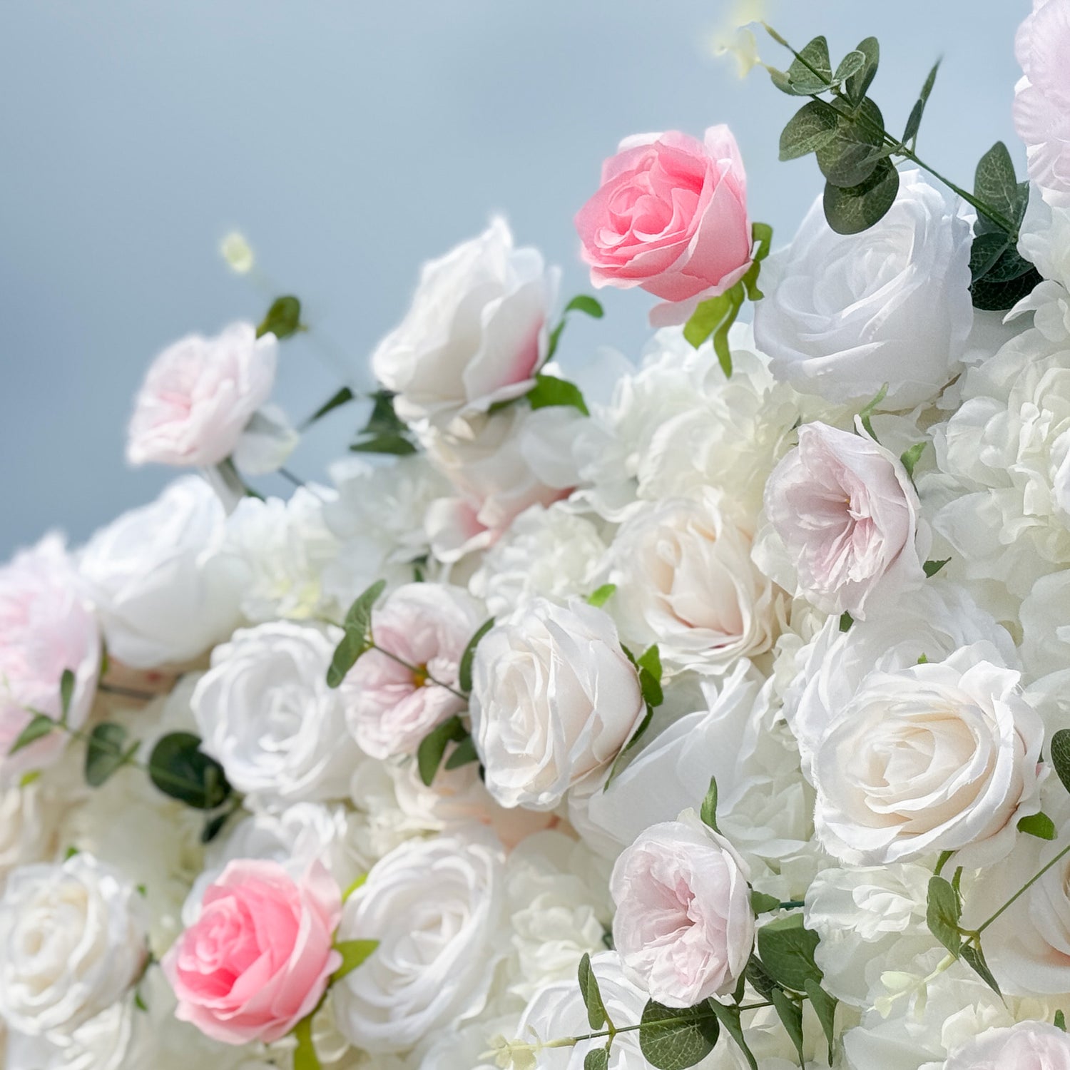 This photo presents a lush floral arrangement, likely artificial roses from ValarFlowers, in soft pink and white, accented with greenery. The dense, realistic blooms create a romantic, elegant ambiance, perfect for weddings or formal events, offering a timeless, dreamy backdrop for memorable moments.