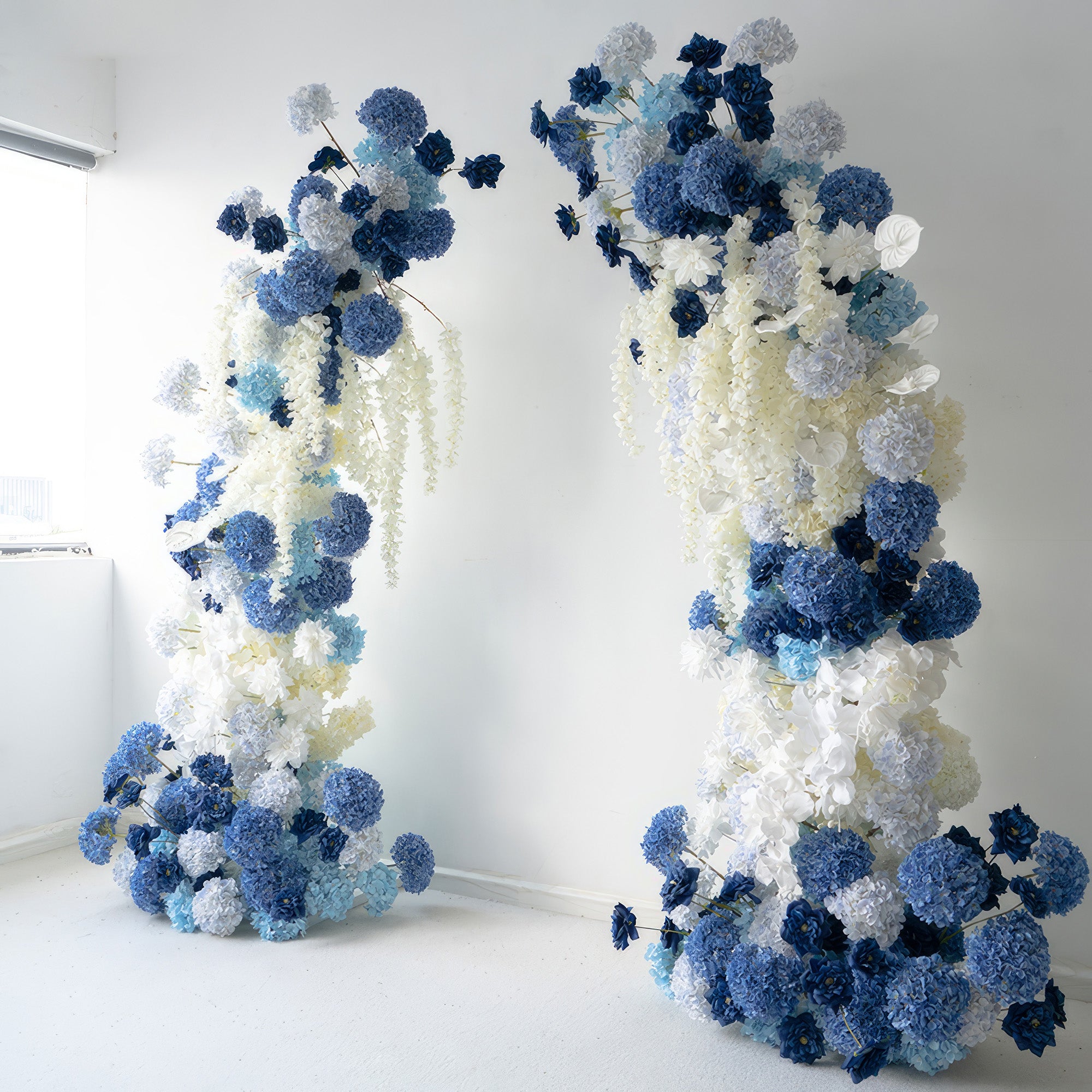 This flower - adorned arch presents a stunning combination of deep blues, light blues, and whites. Abundant with hydrangeas and other blossoms, it conveys a serene and elegant style. Perfect for weddings, events, or photo - ops, it adds a touch of sophistication to any occasion.