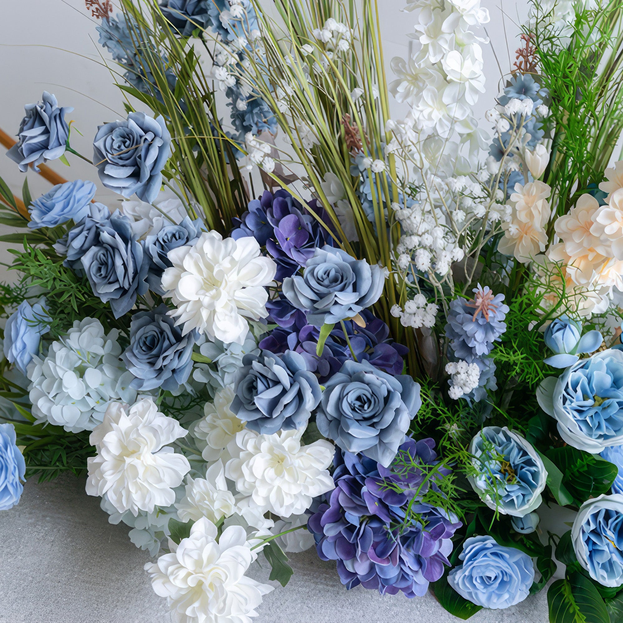 A close-up of a lush floral arrangement from Valar Flowers, featuring a harmonious blend of deep navy, sky blue, creamy white, and soft peach blooms—including roses, hydrangeas, and delicate baby&