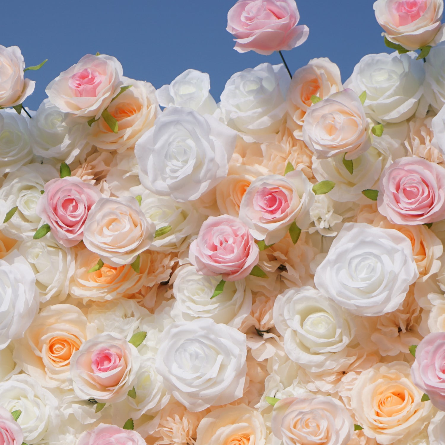 This photo features a lush floral wall of artificial roses, likely by ValarFlowers. The blooms in soft white, peach, and pink hues create a romantic, elegant vibe. Perfect for weddings, the dense arrangement and pastel colors evoke a dreamy, celebratory atmosphere, ideal for capturing memorable moments with timeless beauty.