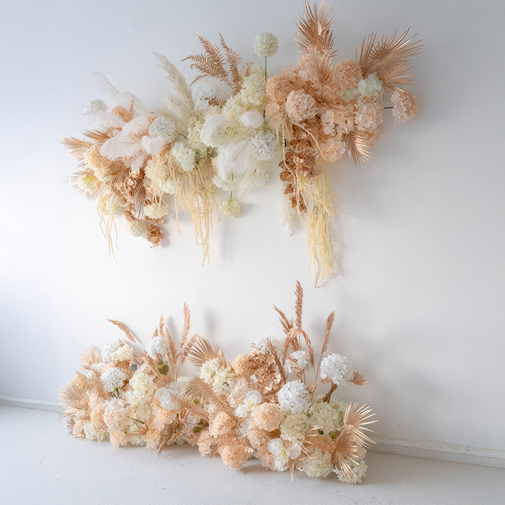 The image features artificial floral arrangements with hydrangeas, palm - like fronds, and feathery elements. In shades of white, peach, and gold, the style is elegant and modern, perfect for event backdrops.