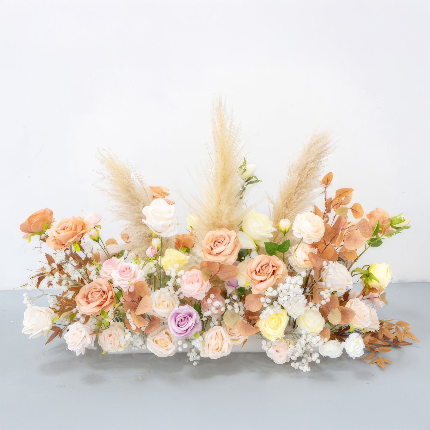 This artificial flower arrangement features roses in soft pastels like peach, pink, lavender, and cream. With pampas grass and brown - hued leaves, it has a warm, natural, and romantic bohemian style.