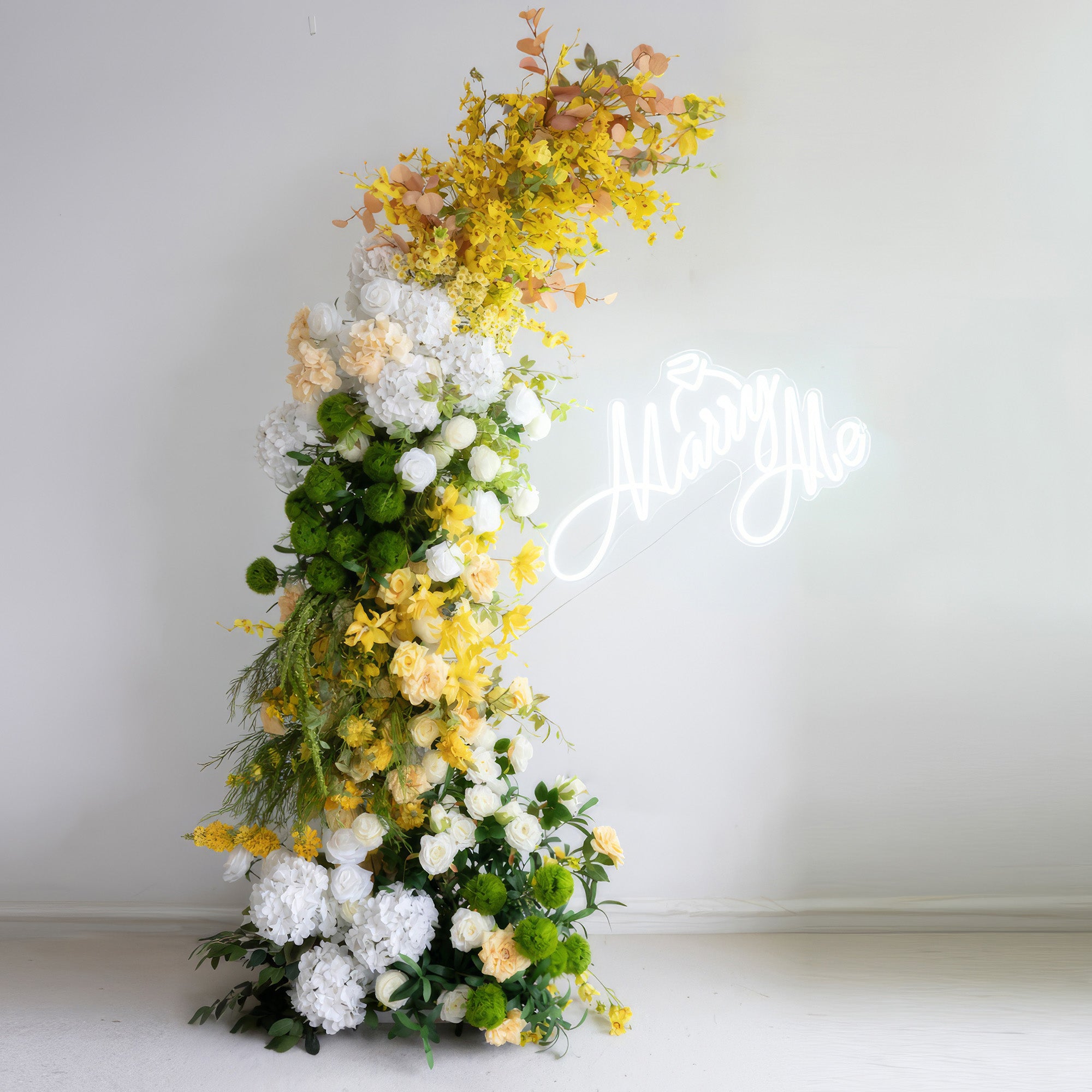 This is an artificial flower arrangement forming a curved structure, boasting a vibrant color palette of bright yellow, pure white, and rich green. It includes large white hydrangeas, yellow flowers, and spherical greenery. With the "Marry Me" neon sign in the background, it conveys a romantic and fresh style.