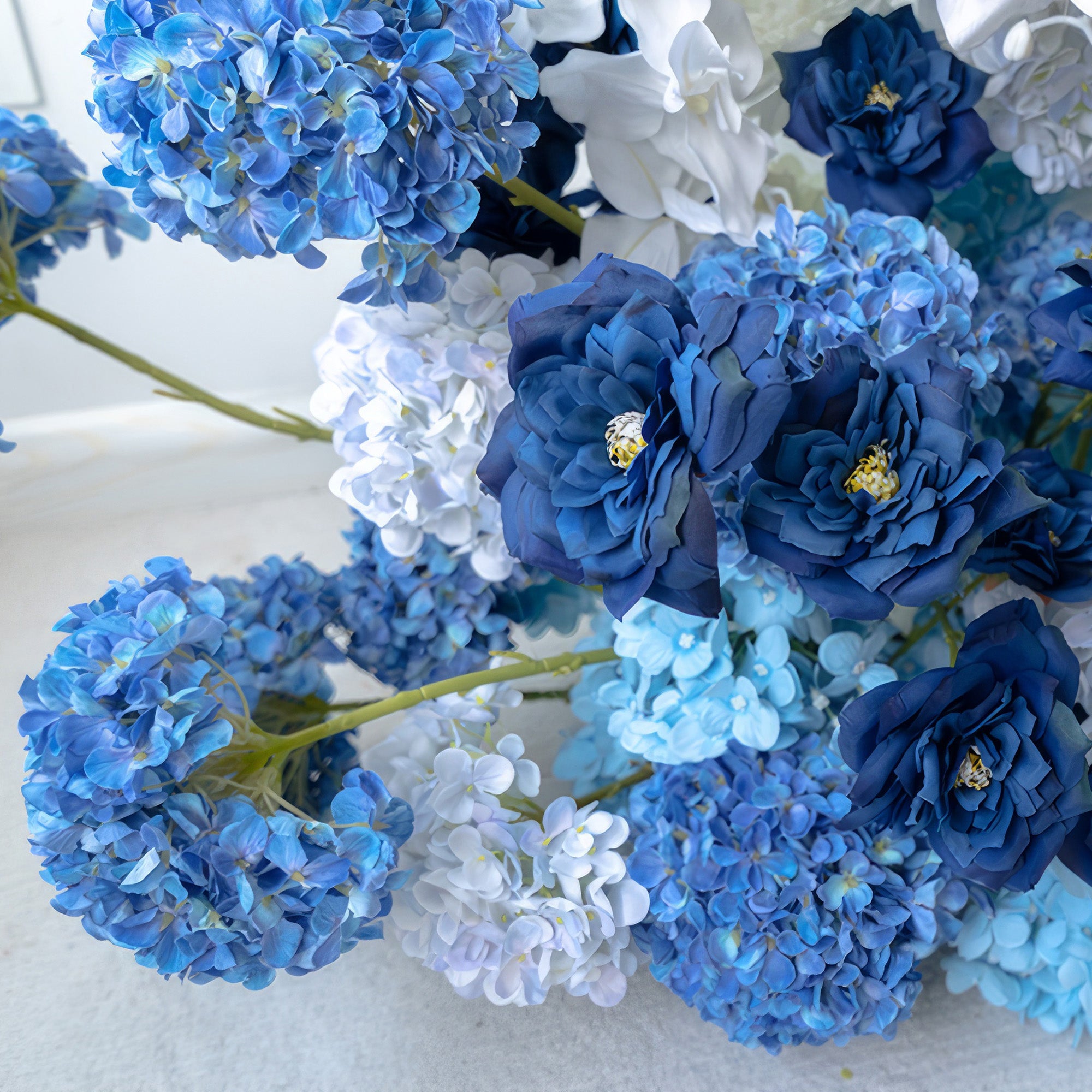 This close - up reveals a captivating mix of deep and light blue hydrangeas along with white blooms. The contrast of the rich blue roses adds a touch of elegance. With its cool - toned palette, it offers a serene and sophisticated style, perfect for events or decor needing a calm, beautiful accent.