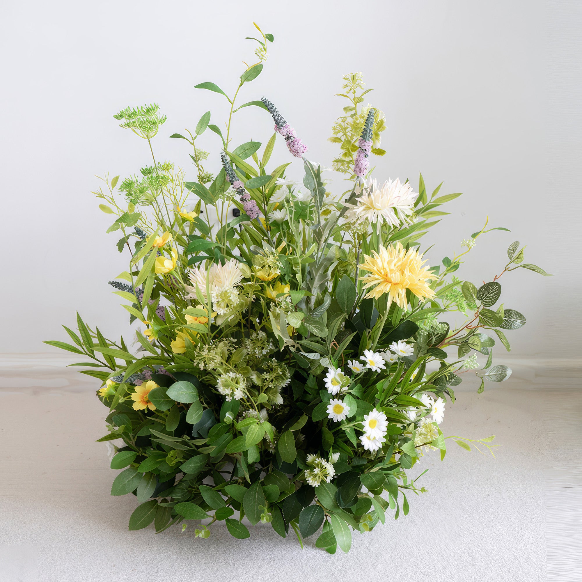 This artificial flower arrangement features a mix of green foliage as the base. Yellow daisies, large yellow blooms, and pale purple spiky flowers add color. It has a fresh, natural, and rustic - like style.