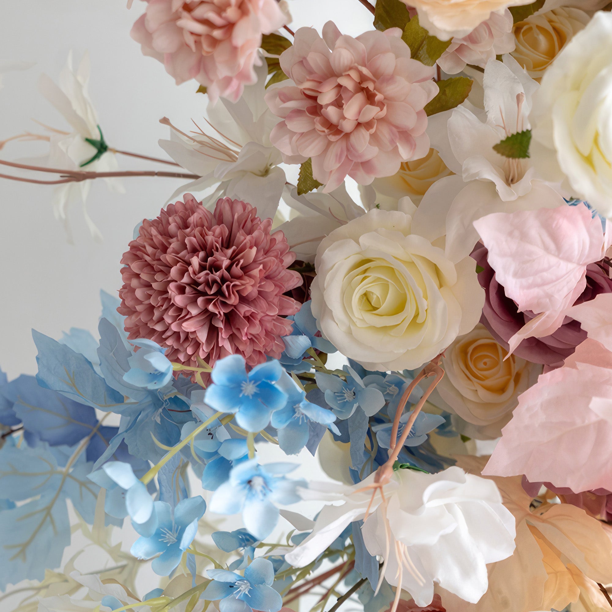 This close - up reveals an enchanting blend of flowers in soft pastel shades like pink, peach, white, and light blue. With roses, dahlias, and small blue blooms, it exudes a gentle, romantic style, ideal for enhancing weddings, parties, or any space needing a touch of elegance.