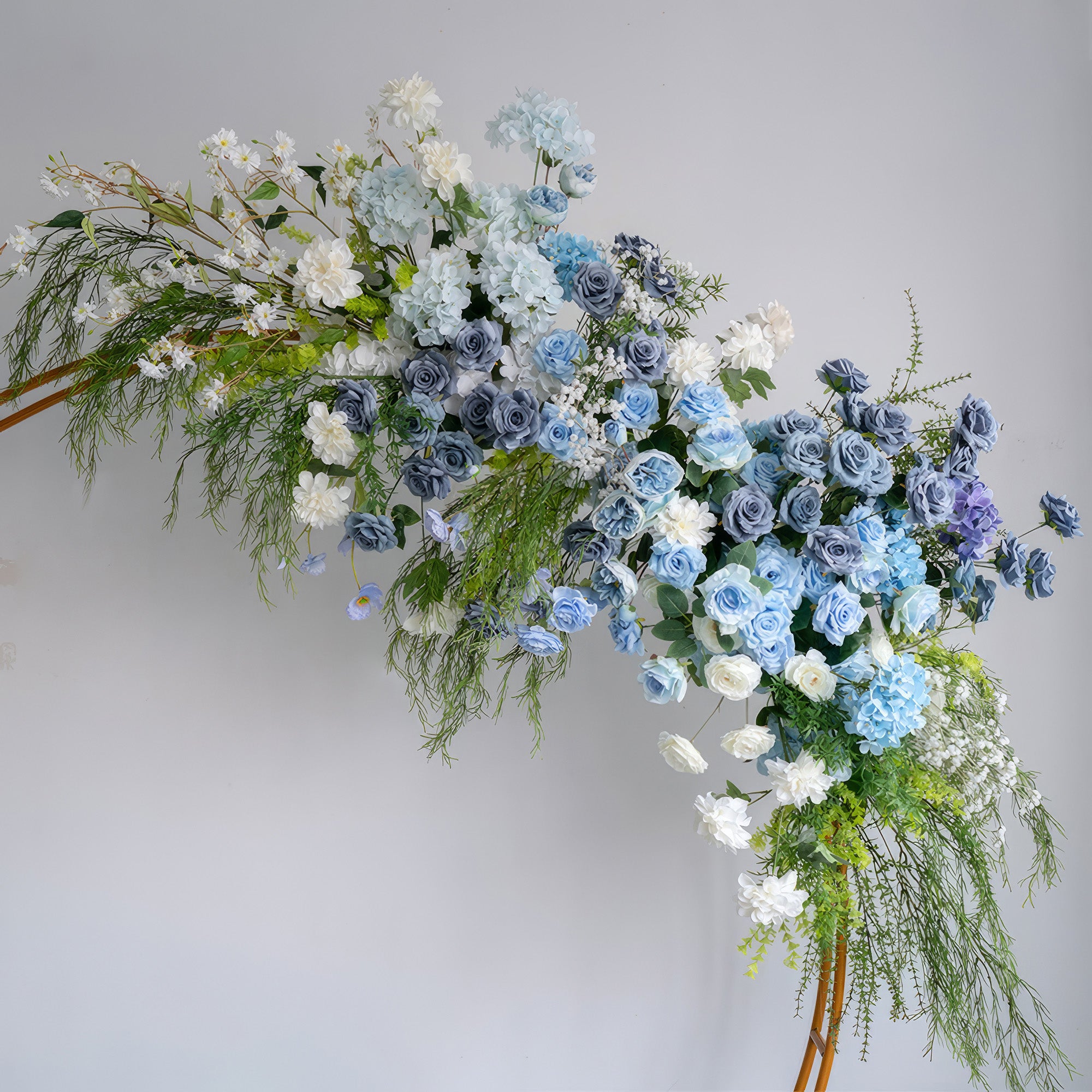 A cascading floral arrangement from Valar Flowers features a serene palette of sky blue, navy, and creamy white blooms—including roses, hydrangeas, and delicate baby&