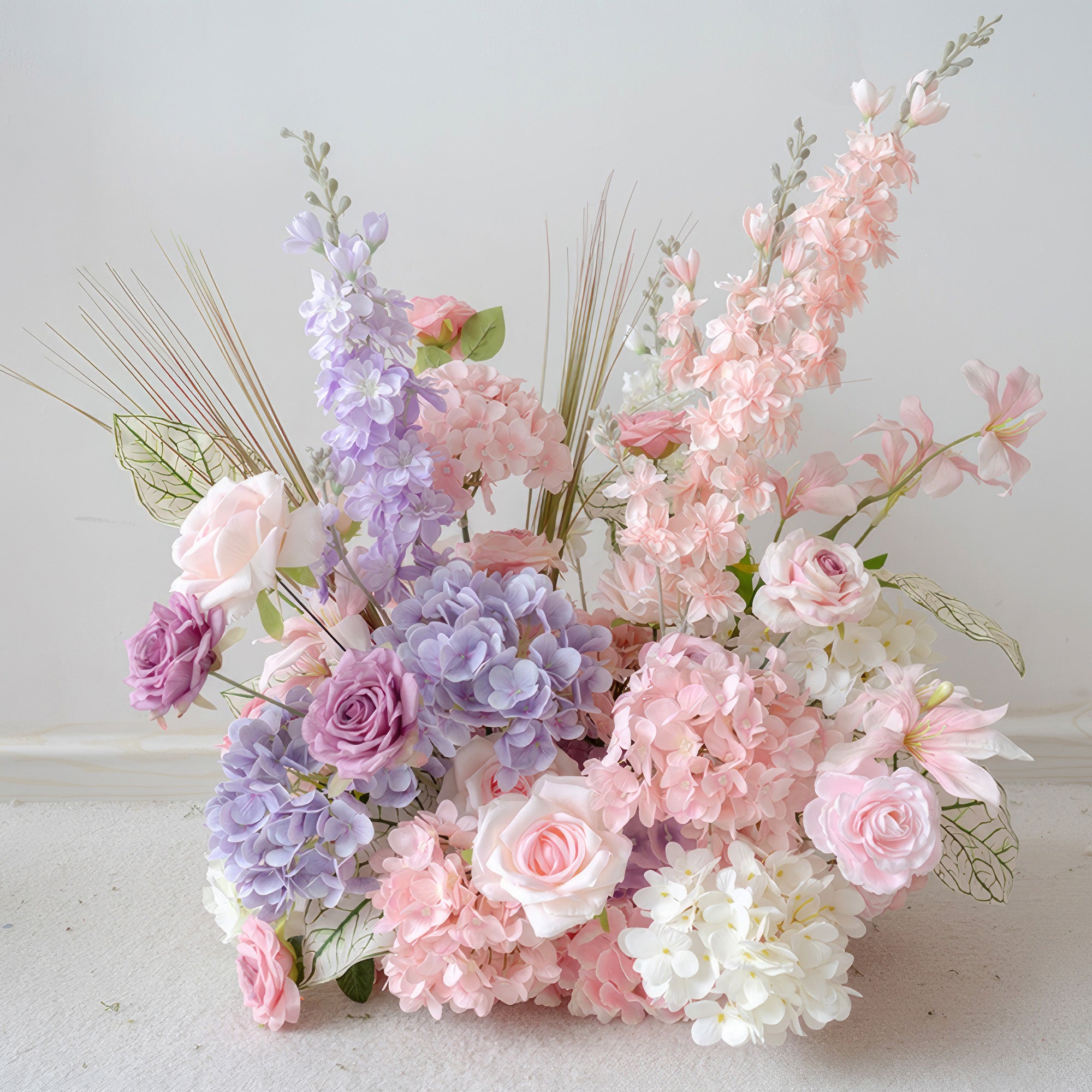 This is a set of artificial flower arrangements primarily in soft pastel colors like light pink, lavender, and white. The floral materials include roses, hydrangeas, along with some slender decorative grass leaves and uniquely - veined foliage. The overall style is romantic and delicate, making it perfect for decorating romantic occasions such as weddings and parties, and it can create a warm and dreamy atmosphere.