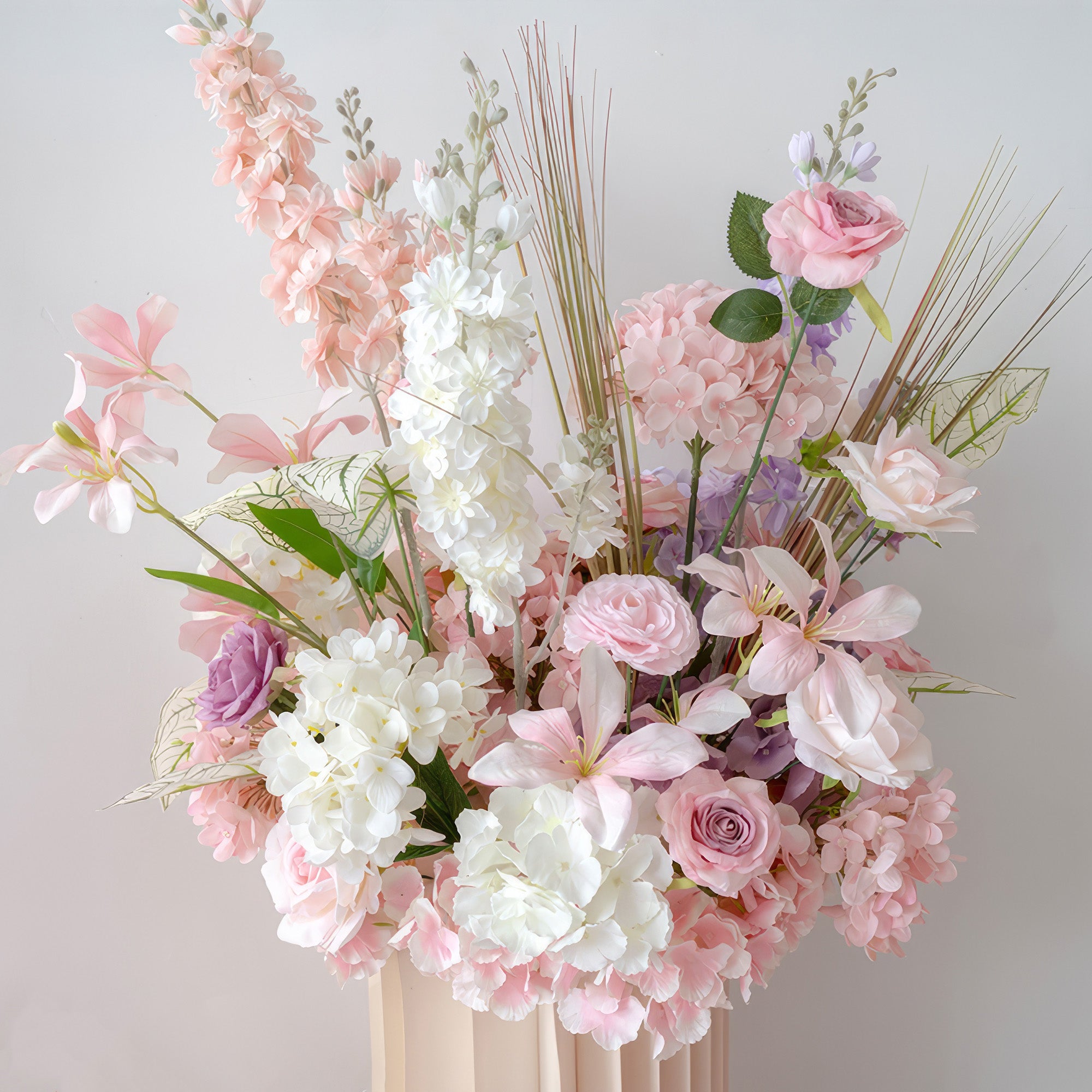 This image features a stunning floral arrangement in a beige vase. It combines soft pastel hues like pink, lavender, and white. With roses, hydrangeas, and other blooms, it exudes a romantic and elegant style.