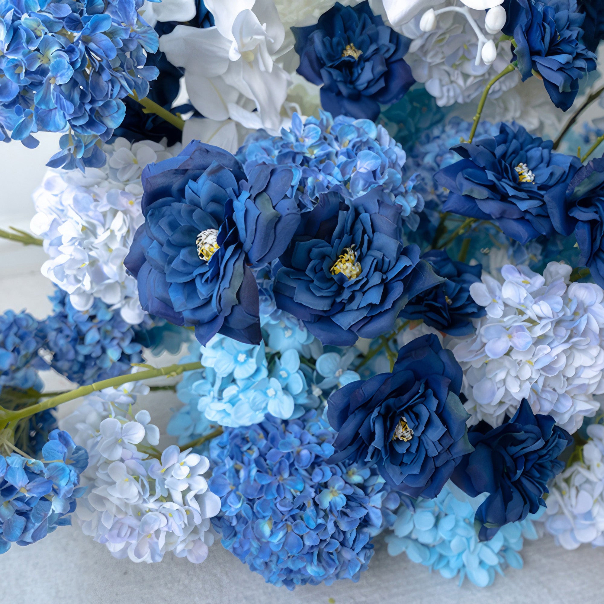 This close - up of the floral arrangement highlights deep blue roses paired with light and medium blue hydrangeas, along with white blossoms. The cool color palette creates a serene and elegant style, ideal for adding a sophisticated touch to events like weddings or to beautify interior spaces.