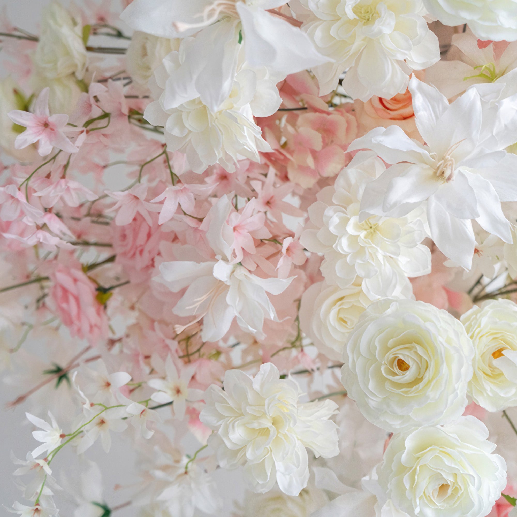 This image showcases an arrangement of artificial flowers. There are roses and other blooms in soft white, light pink, and peach hues. The style is romantic and delicate, creating a gentle and charming atmosphere.