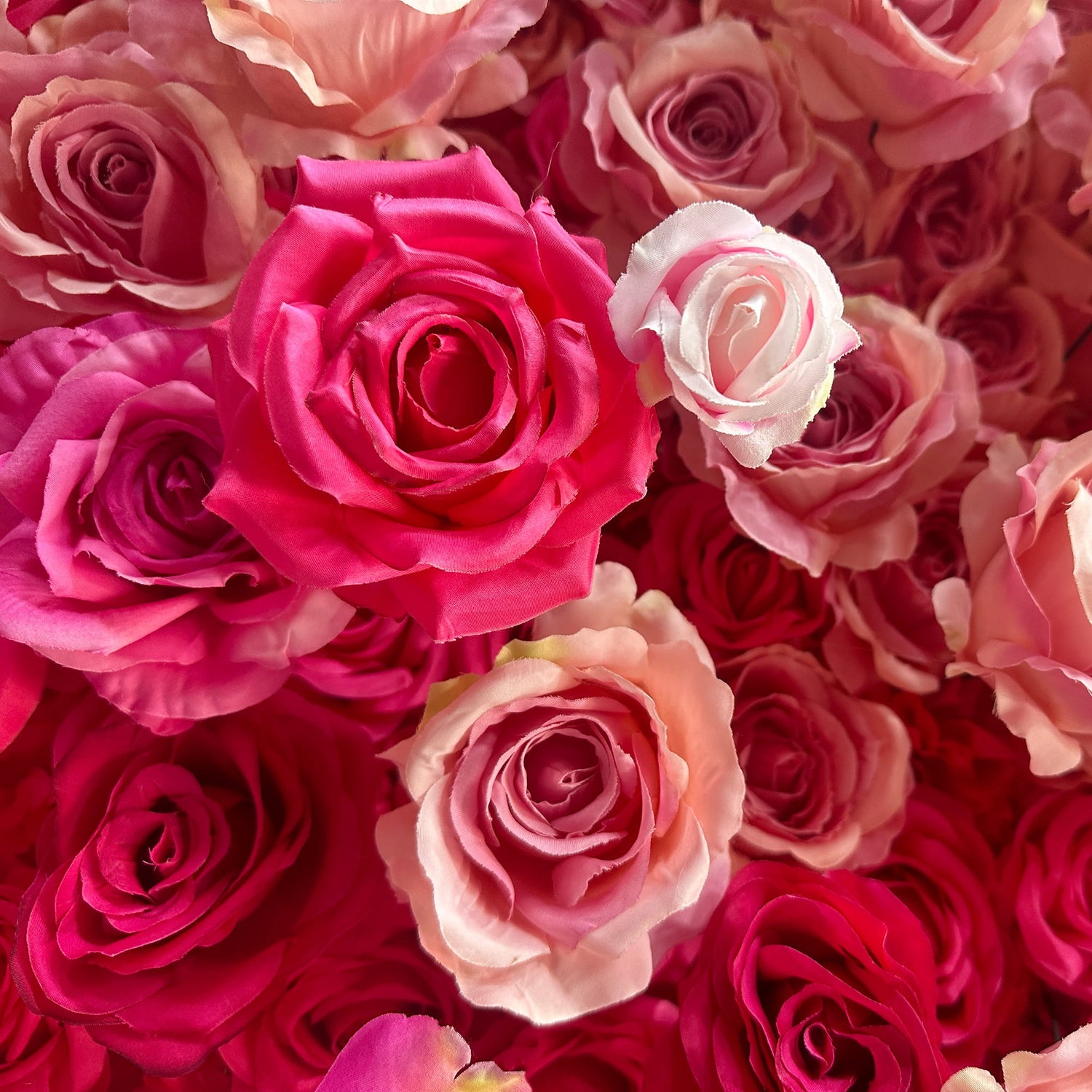 This image features a dense arrangement of artificial roses in a rich palette of colors. Predominant hues range from deep magenta to soft pastel pinks and peaches. The roses vary in size and petal arrangement, creating a lush and textured appearance. The overall style is romantic and vibrant, making it perfect for event decorations, such as weddings or photo - backdrops.