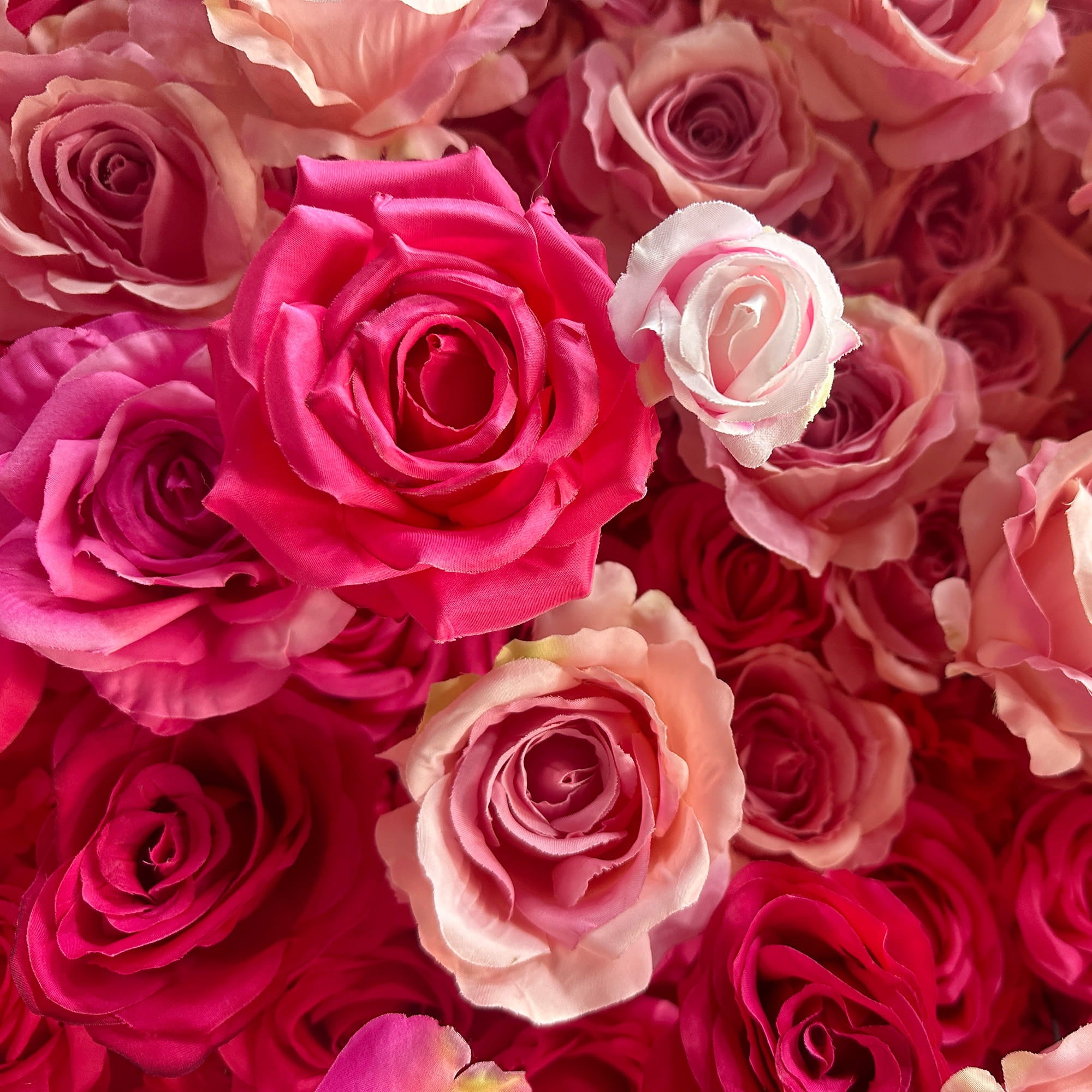 This image features a dense arrangement of artificial roses in a rich palette of colors. Predominant hues range from deep magenta to soft pastel pinks and peaches. The roses vary in size and petal arrangement, creating a lush and textured appearance. The overall style is romantic and vibrant, making it perfect for event decorations, such as weddings or photo - backdrops.
