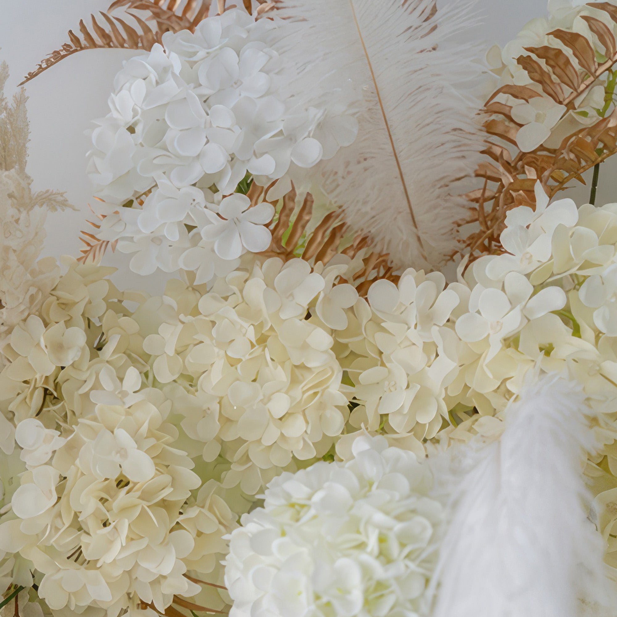 This image showcases artificial hydrangea flowers in pure white and creamy tones, interspersed with white feathers and brown - hued fern - like foliage. The style is elegant and soft, suitable for a refined decor.