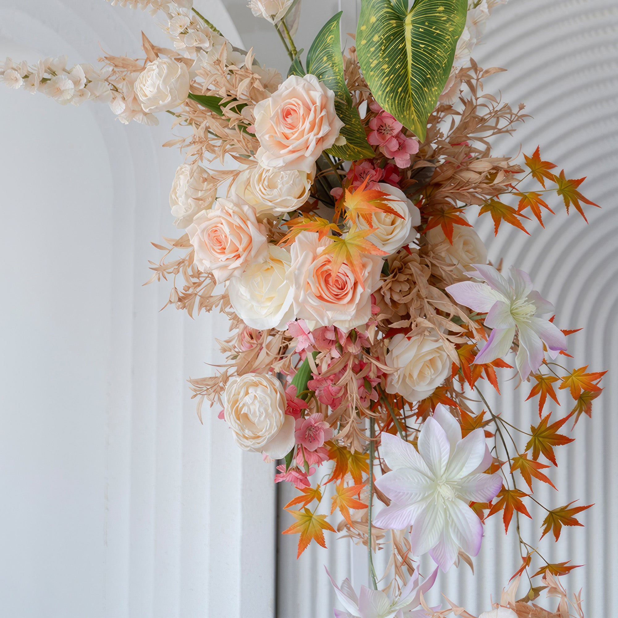 This image features an artificial flower arrangement with roses, small pink blossoms, and other blooms. Colors range from soft peach and white to pink and orange - tinged leaves. The style is natural and romantic.