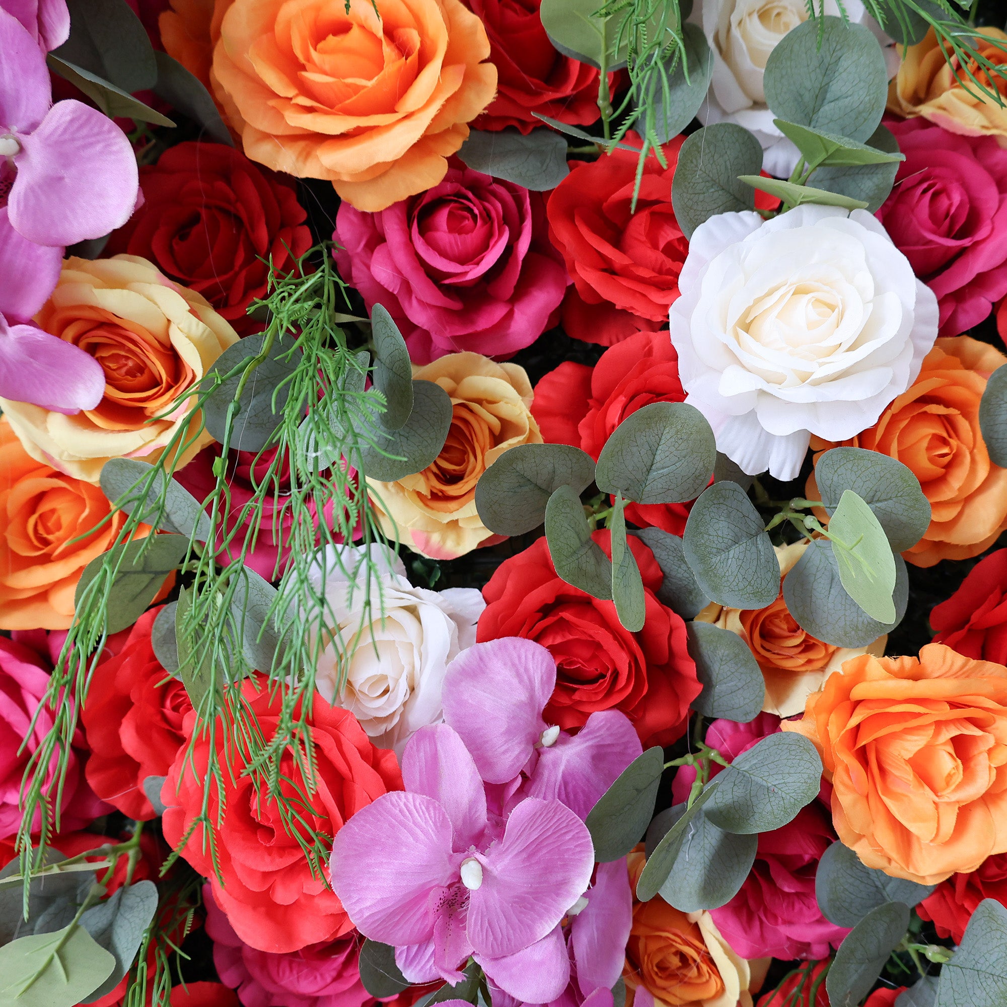This image showcases a vibrant floral arrangement by Valar Flowers. It features a dense cluster of artificial flowers in a rich palette of red, orange, pink, and white, including roses and orchids, interspersed with lush green foliage. The blooms are intricately arranged to create a lush, textured, and visually striking display. Perfect for adding a touch of energy and elegance to events or spaces, the arrangement exudes a lively and sophisticated atmosphere.