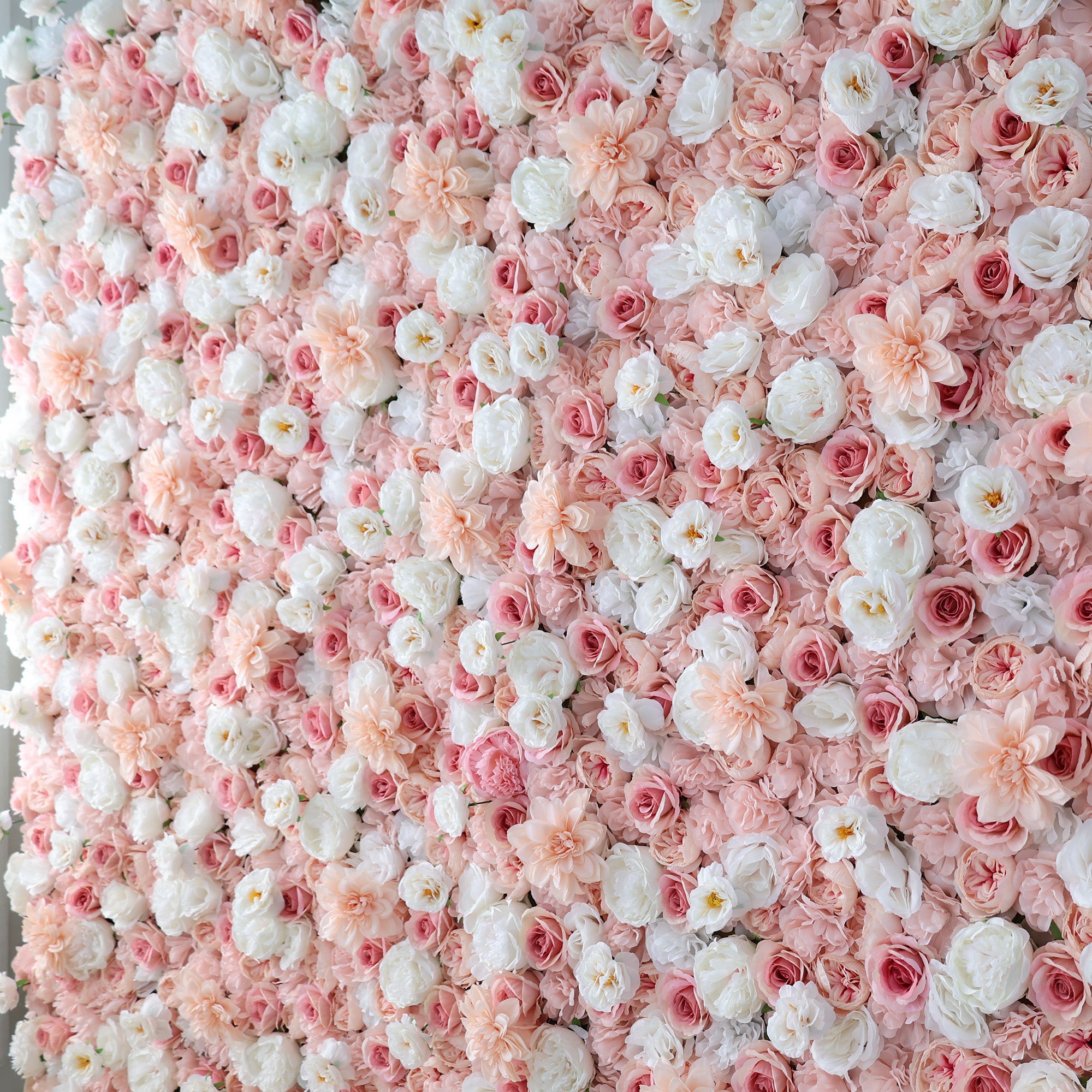A dense wall of artificial flowers showcases a beautiful mix of pink, blush, and white blooms. Various floral types, including roses and other delicate blossoms, create a lush, romantic arrangement. The soft color palette and abundant display exude elegance, making it perfect for events like weddings, photo backdrops, or upscale gatherings needing a charming, floral focal point.