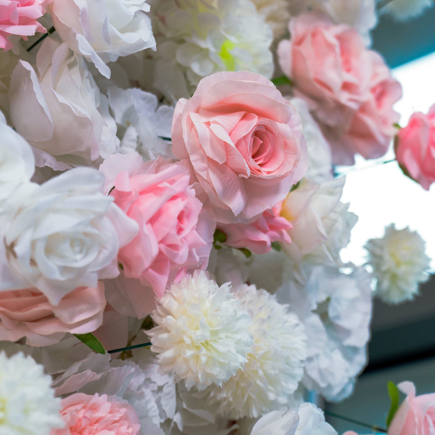 A close - up of a floral wall with a mix of pink and white roses. The flowers are arranged in a way that creates a soft and romantic atmosphere.