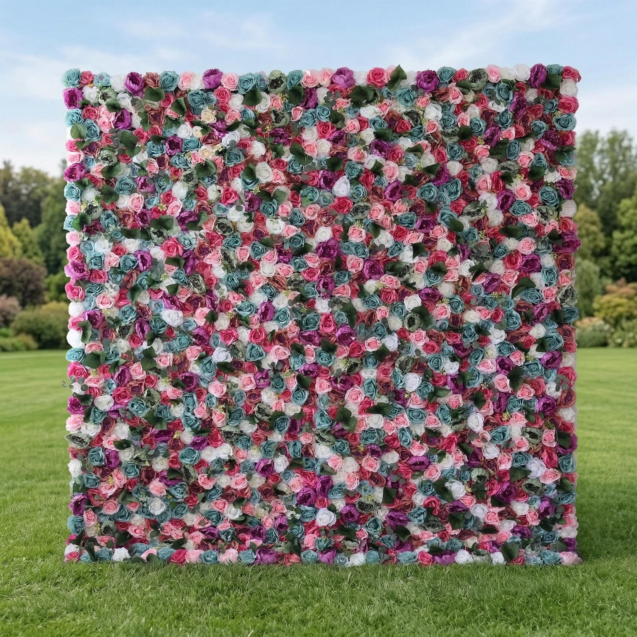 This striking Valar Flowers floral wall boasts a vibrant, multicolored mosaic of blooms—featuring vivid magenta, deep purple, teal, and rose-pink roses—densely packed against a serene sky and lush green grass. Its bold, rainbow-inspired palette creates a visually stunning, festive backdrop perfect for lively celebrations, outdoor parties, and dramatic photo shoots.