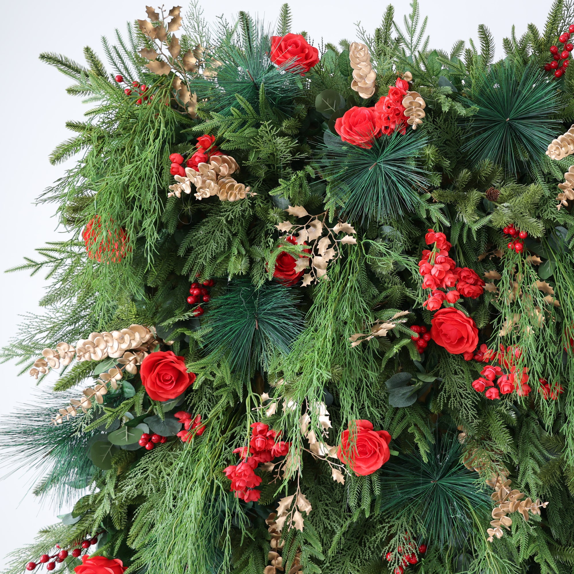 This image showcases a lush, festive arrangement, likely for Christmas. It features abundant green foliage, vibrant red roses, and clusters of red berries. Accents of golden - hued leaves add an elegant touch. The dense, rich composition exudes a warm, holiday charm, perfect for creating a joyful and celebratory atmosphere, ideal for seasonal decorations.