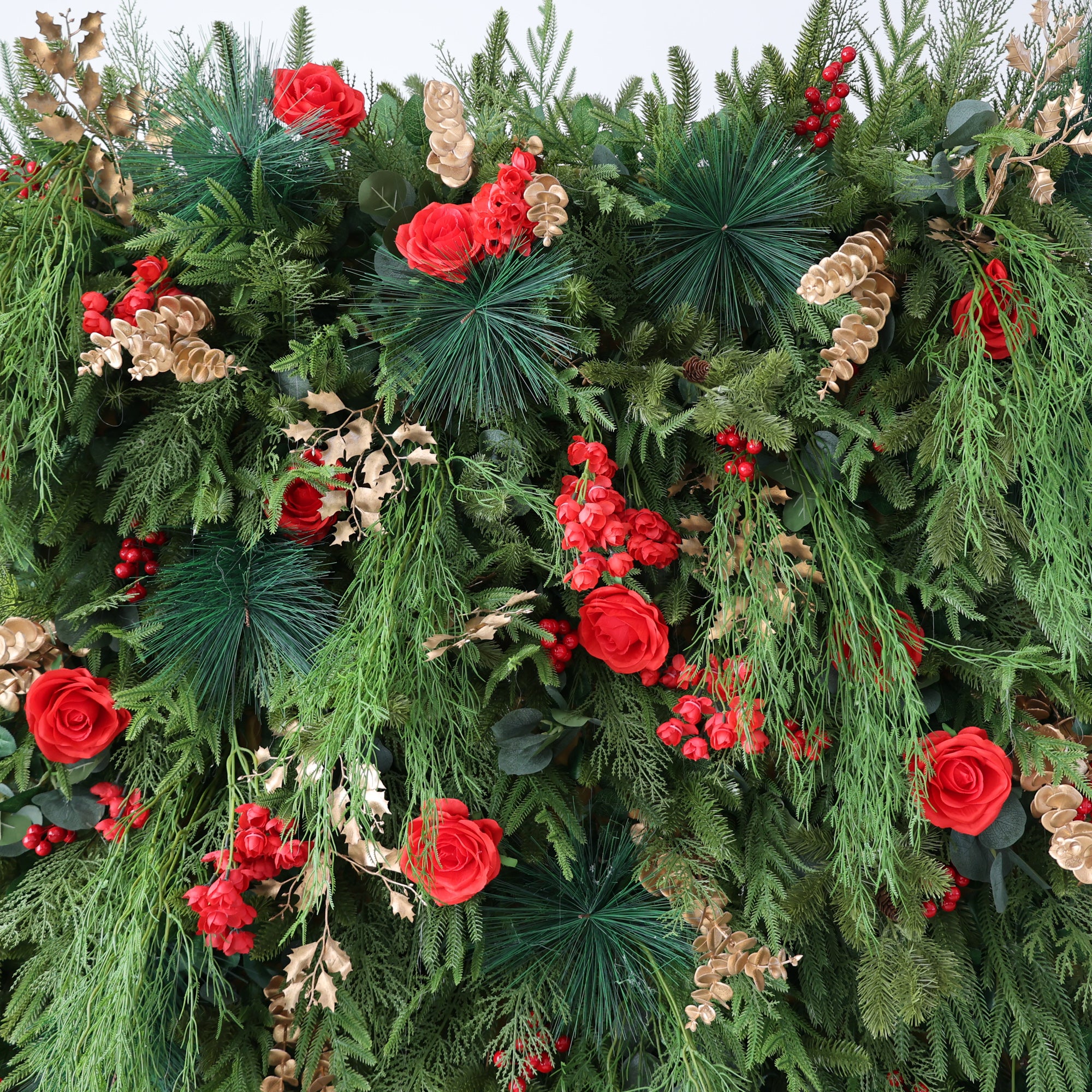 This image presents a lush, festive floral arrangement, likely for a holiday like Christmas. It features abundant green foliage, vibrant red roses, and clusters of red berries. Accents of golden - hued leaves add an elegant touch. The dense, rich composition exudes a warm, celebratory charm, perfect for creating a joyful and inviting atmosphere, ideal for seasonal decorations.