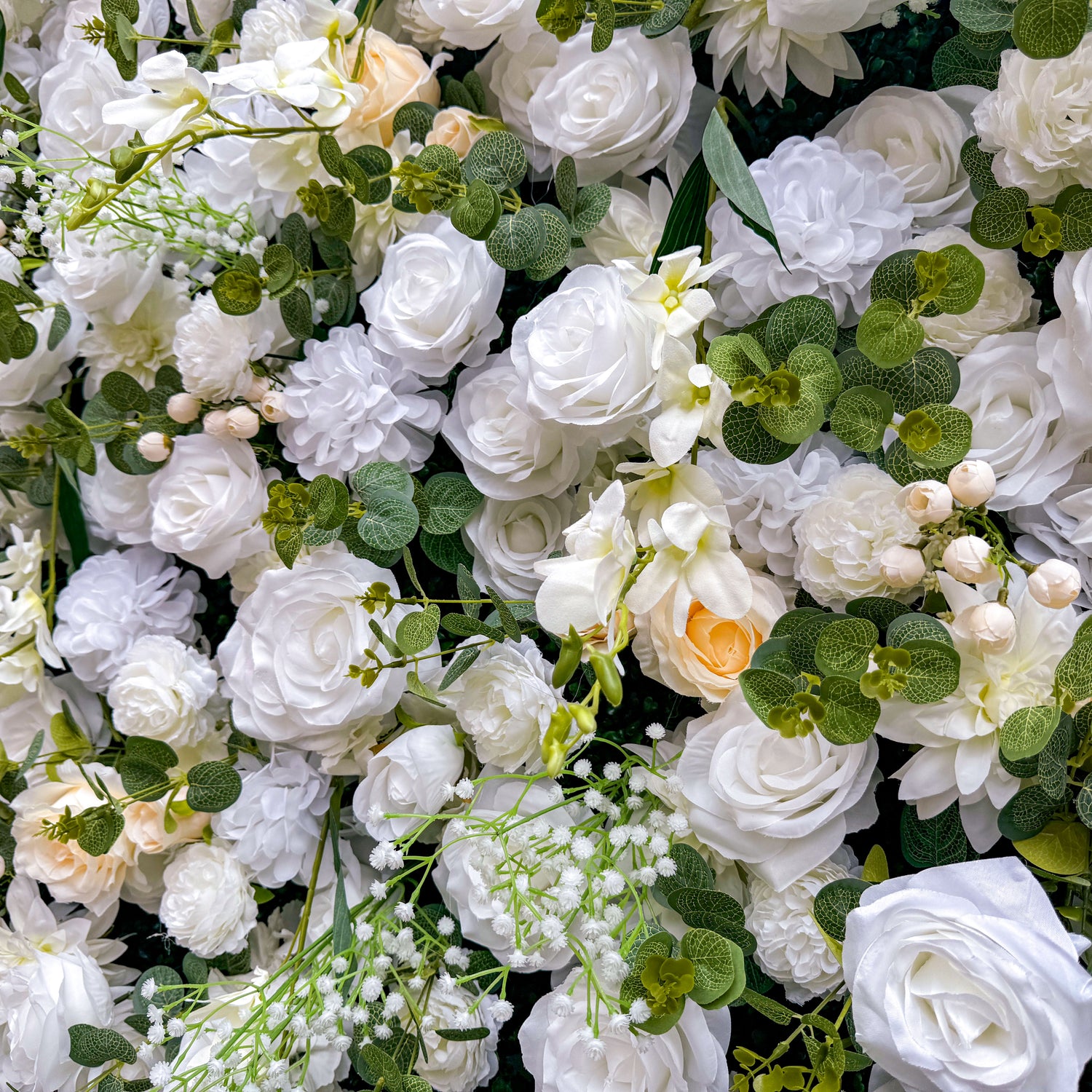 This artificial flower wall is a sight to behold. It is densely packed with a variety of white and cream - colored flowers, such as roses and lilies. The flowers are complemented by lush green leaves, creating a rich and elegant appearance. It is perfect for weddings or events, providing a romantic and beautiful backdrop.