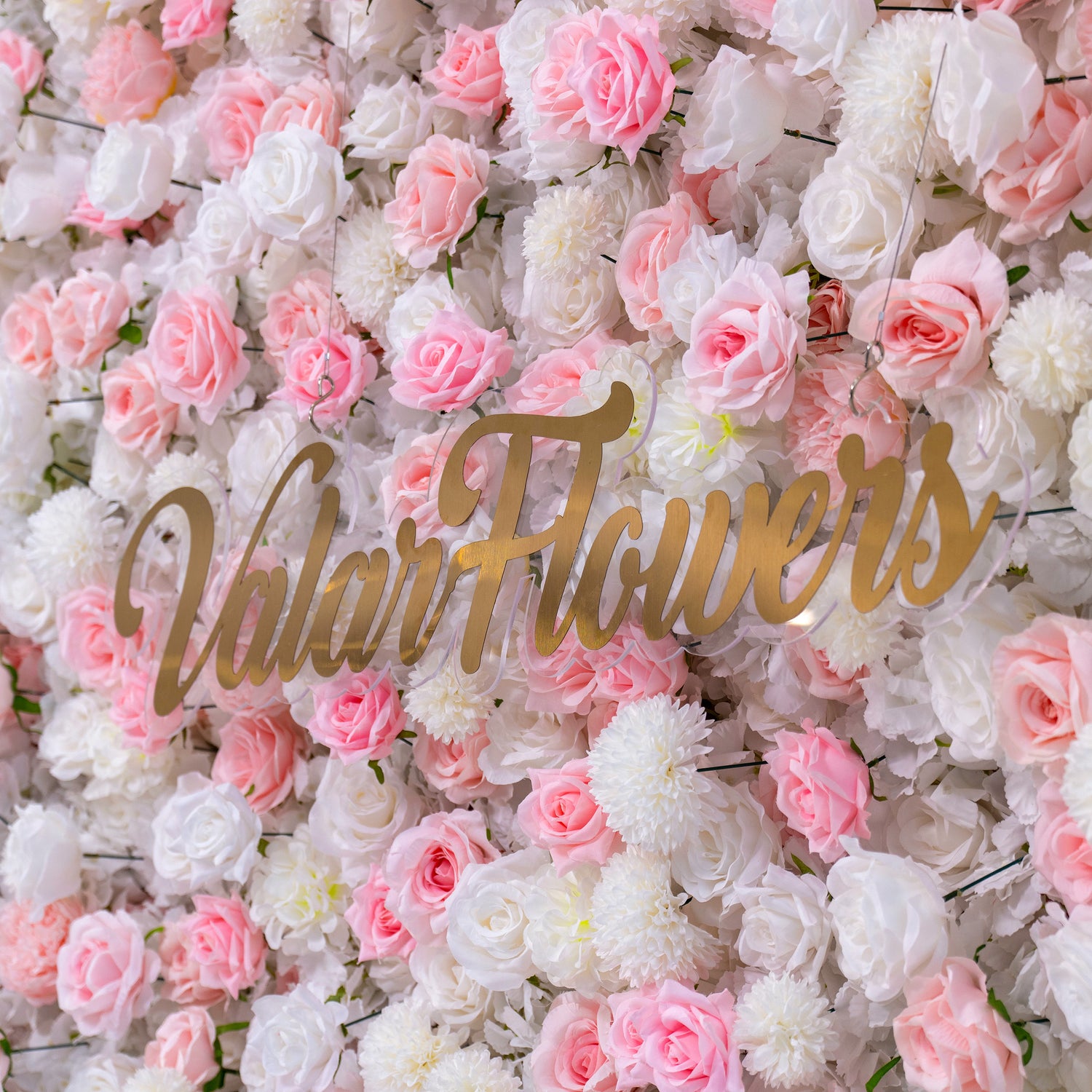 The image shows a beautiful floral wall with pink and white flowers. The text "Valar Flowers" is prominently displayed in the center. This setup is ideal for weddings or events as a decorative backdrop.