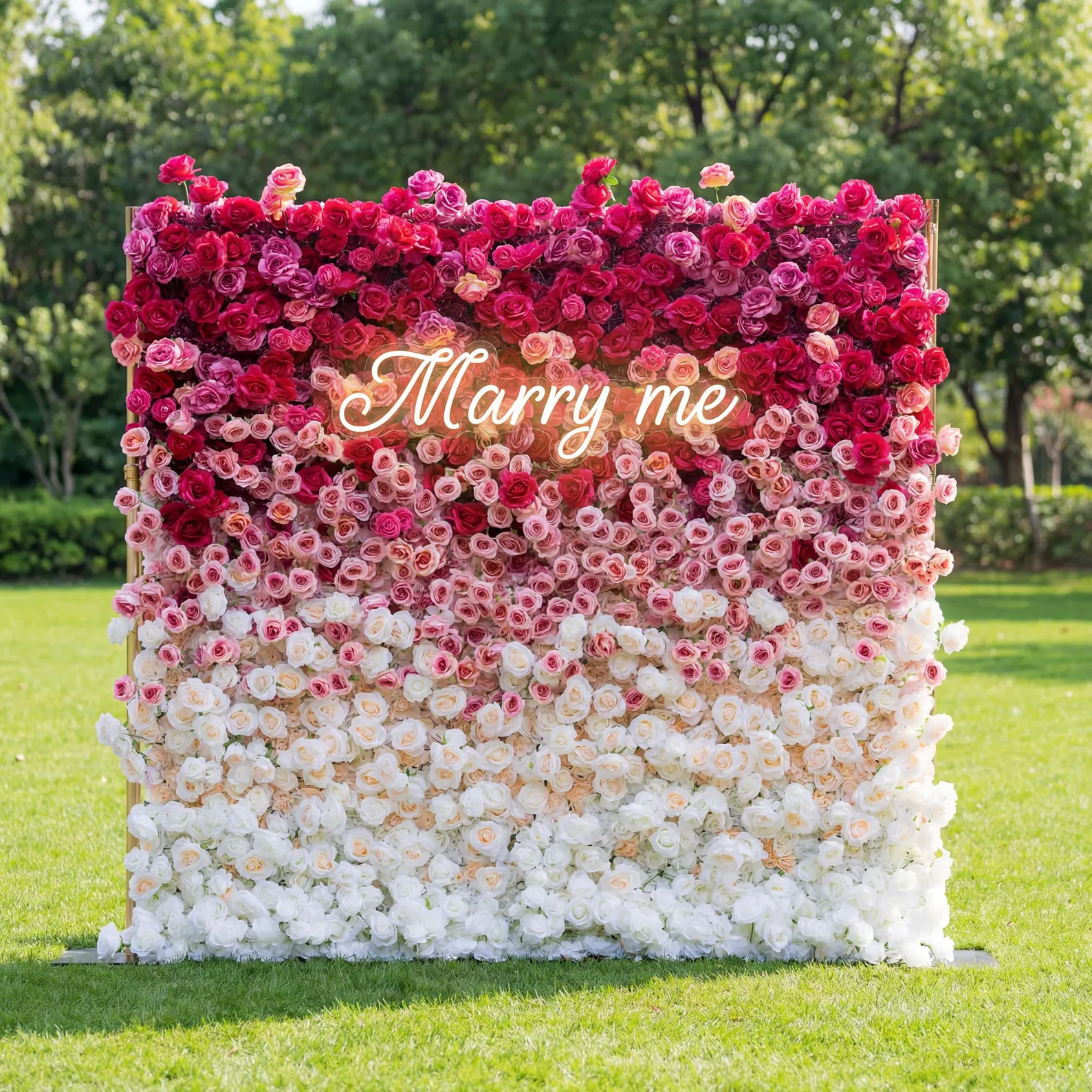 This is a romantic, gradient artificial flower wall backdrop from Valar Flowers, transitioning from deep red roses at the top to soft pink and pure white blooms at the bottom. A translucent "Marry me" sign overlays the center, set against a lush green lawn and trees, creating a dreamy, heartfelt setting perfect for marriage proposals, weddings, or special photo shoots.