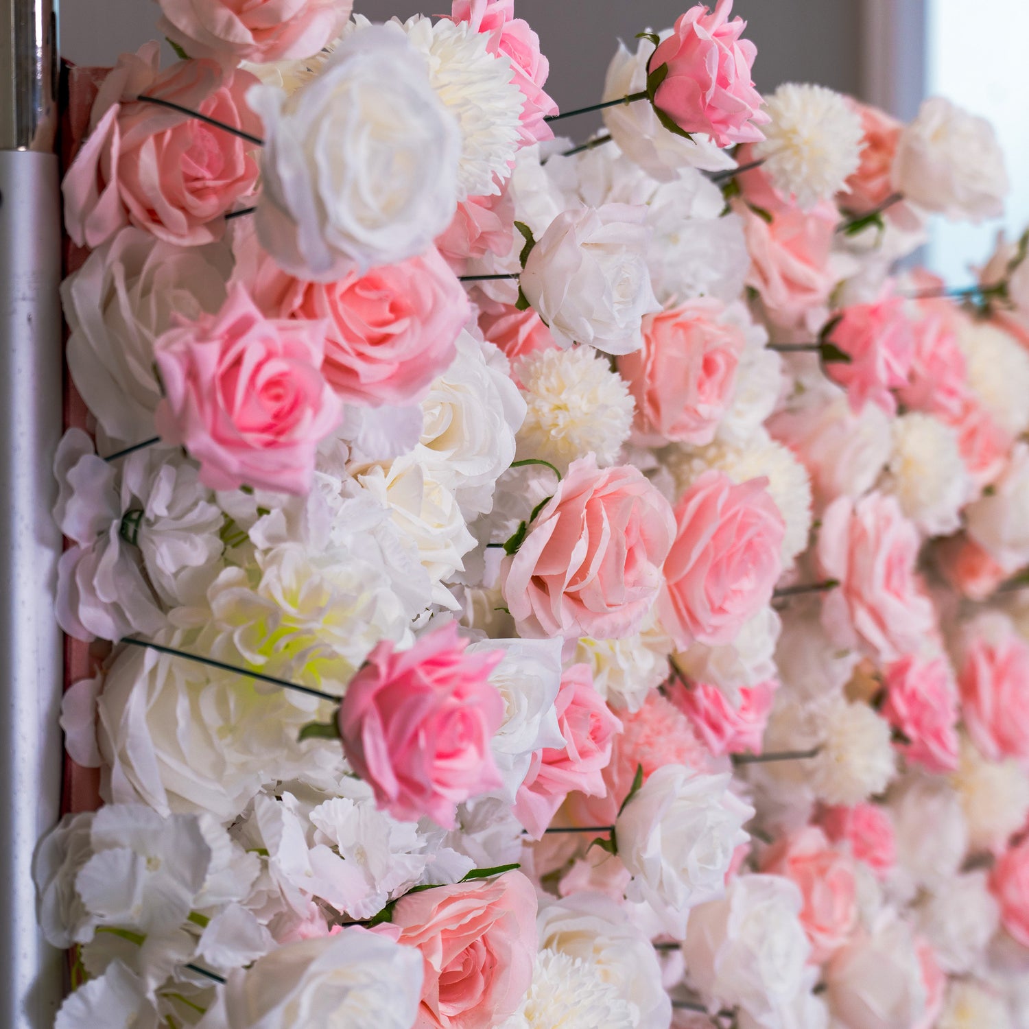 A section of a floral wall adorned with an abundance of pink and white roses. The flowers are densely packed, creating a lush and romantic display.
