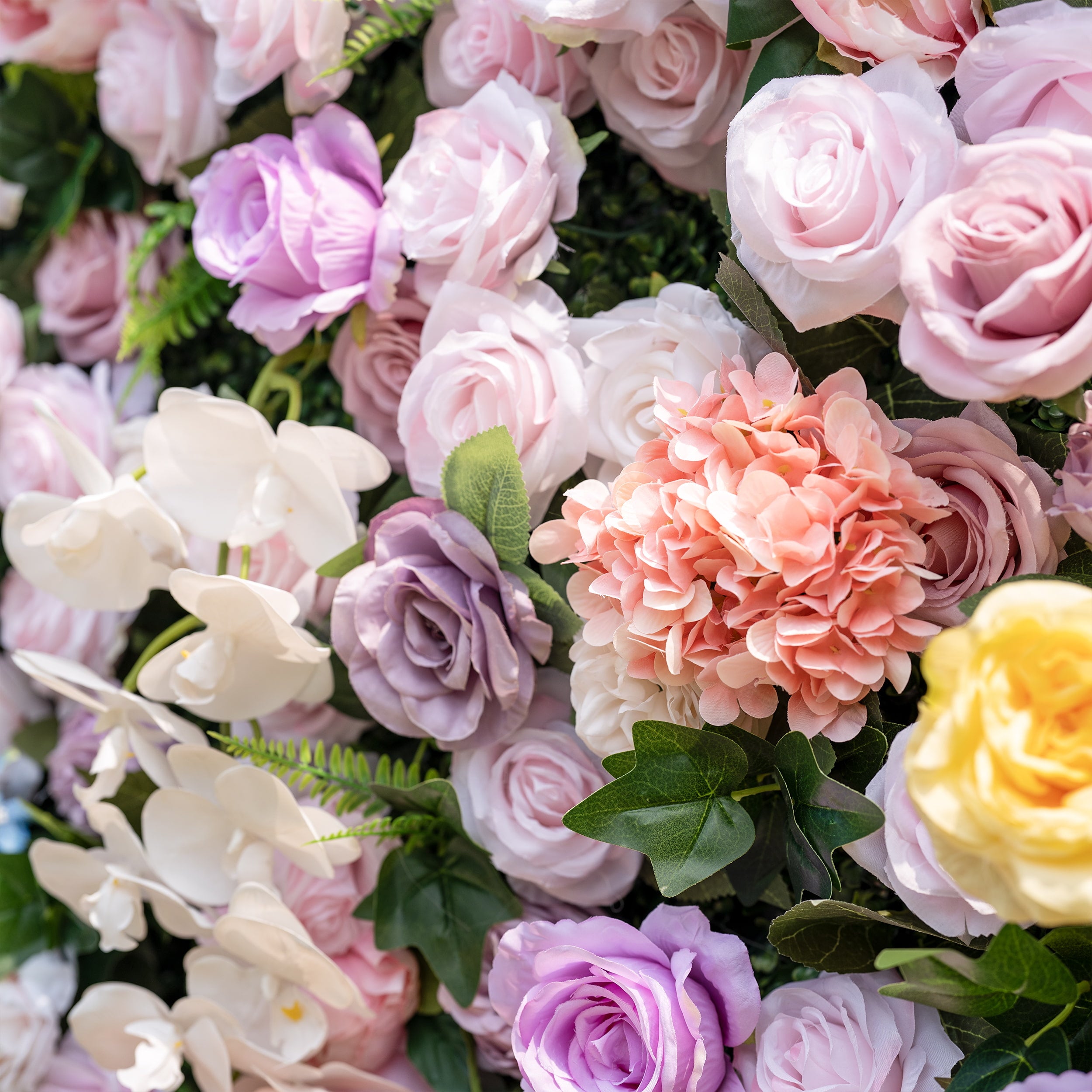 This is a lush, premium artificial flower wall arrangement, brimming with lifelike blooms in a dreamy romantic palette. It features blush pink roses, lavender roses, creamy white phalaenopsis orchids, vibrant pink hydrangeas, sunny yellow roses, and realistic green foliage. The dense, high-quality design creates an elegant, timeless focal point, perfect for wedding backdrops, photo booths, bridal showers, baby showers, and luxury event decor.