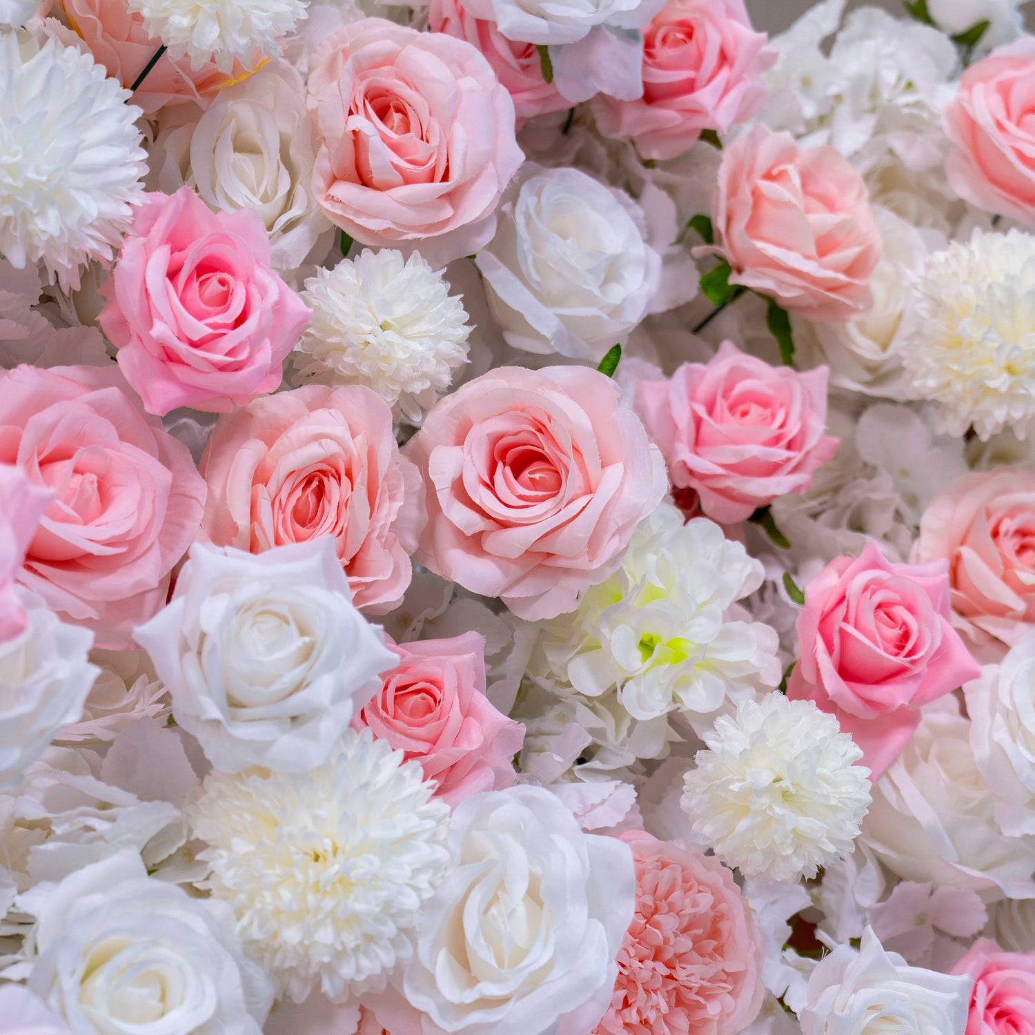 A detailed view of a floral wall featuring predominantly pink and white roses. The roses are arranged closely together, giving a rich and full appearance.