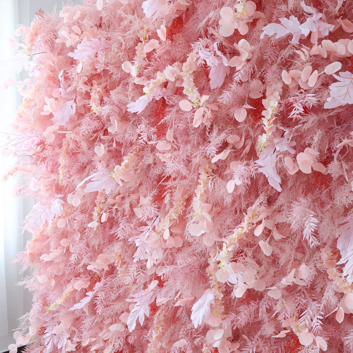 This close - up image showcases a dense arrangement of artificial pink flowers and foliage. The flowers, with their soft pink hues and delicate petals, are clustered tightly to form a lush, romantic floral display. The harmonious blend of various pink shades and intricate botanical elements creates a gentle and elegant scene, ideal for decorative purposes in events or as a visually appealing artistic display.