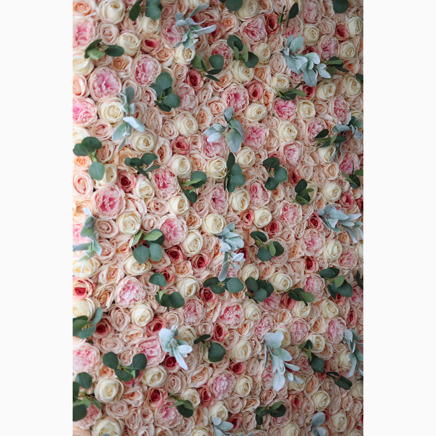 A large artificial flower wall features a harmonious mix of soft - pink, peach, and cream roses. Interspersed are green eucalyptus leaves and light - toned foliage, adding texture. The dense, layered arrangement creates a lush, romantic backdrop, ideal for adding elegance to events.