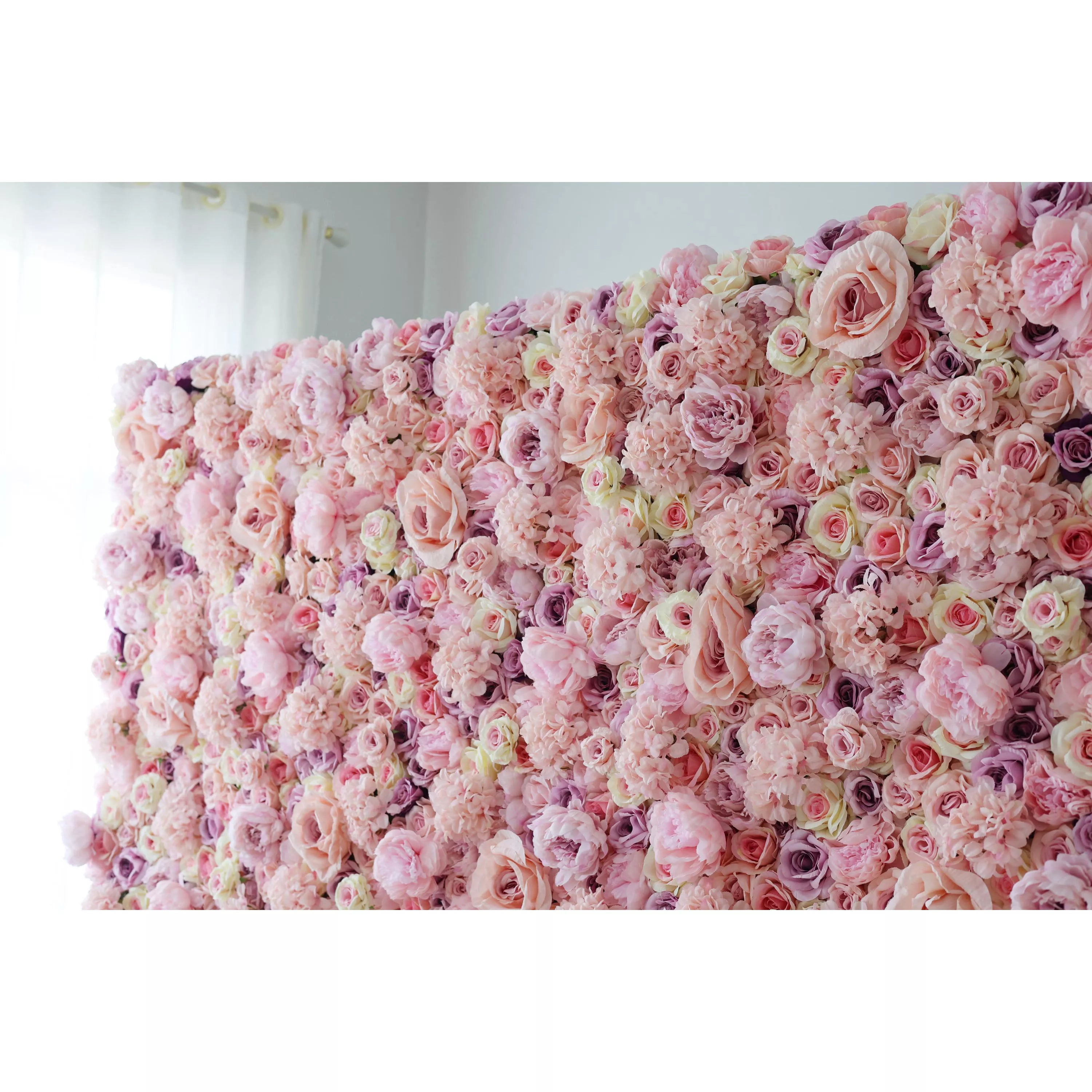 This indoor floral wall is a dense, immersive expanse of artificial blooms in a soft, romantic palette of blush pink, ivory, and subtle lavender. It features large, ruffled roses, delicate peonies, and clustered filler flowers, creating a rich, multi-textured surface. The gentle gradient of pastel tones and varied bloom sizes evoke a dreamy, timeless elegance, making it ideal for wedding backdrops, photo booths, or upscale interiors seeking a feminine, romantic focal point.