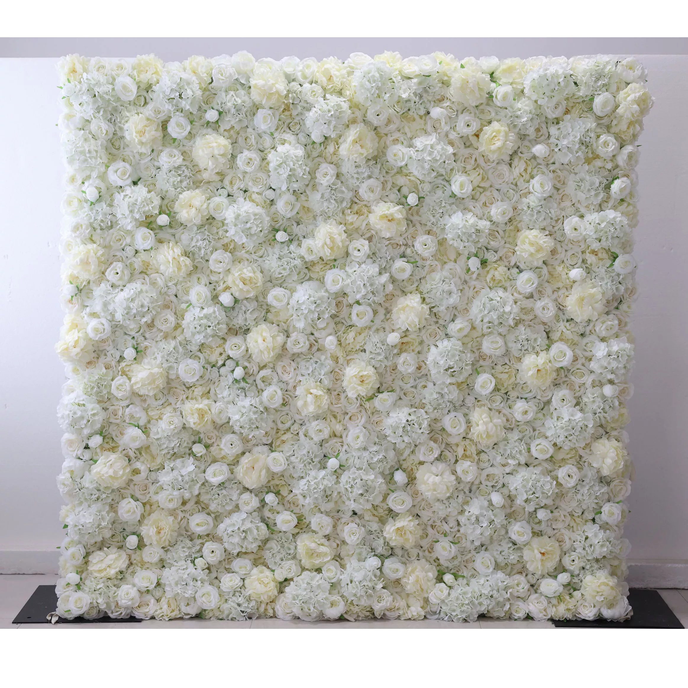 This elegant indoor floral backdrop features a dense, velvety arrangement of artificial white and cream roses, layered with delicate filler blooms to create a lush, three-dimensional texture. Its soft, luminous palette exudes timeless sophistication and romance, making it a stunning focal point for weddings, engagement photos, or upscale events against a minimalist white wall.