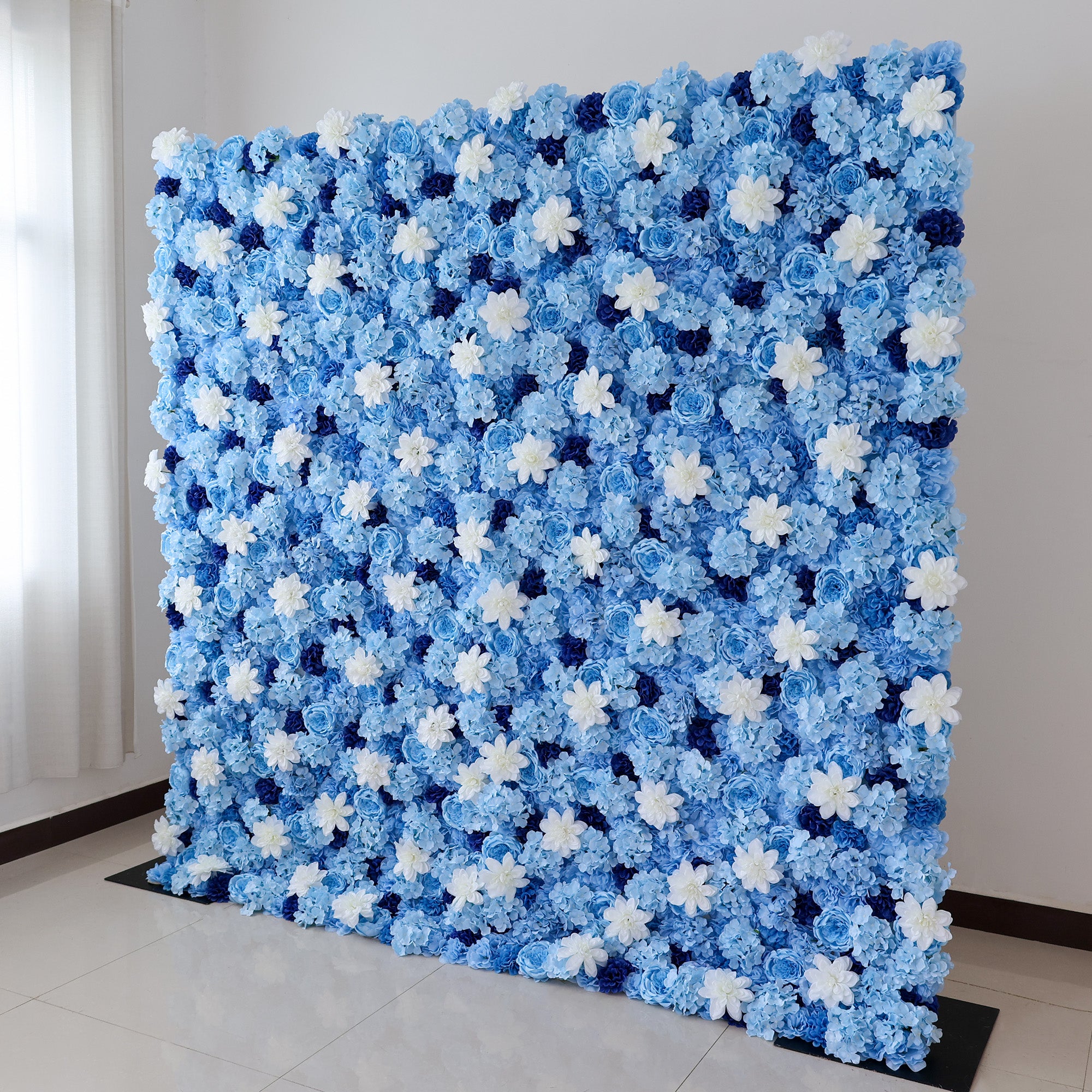 A large artificial flower wall showcases a stunning arrangement of blue hydrangeas, white daisy - like blooms, and dark blue blossoms. The dense, evenly - spaced pattern creates a serene, elegant backdrop, perfect for events or decorative displays, evoking a calm and sophisticated ambiance.