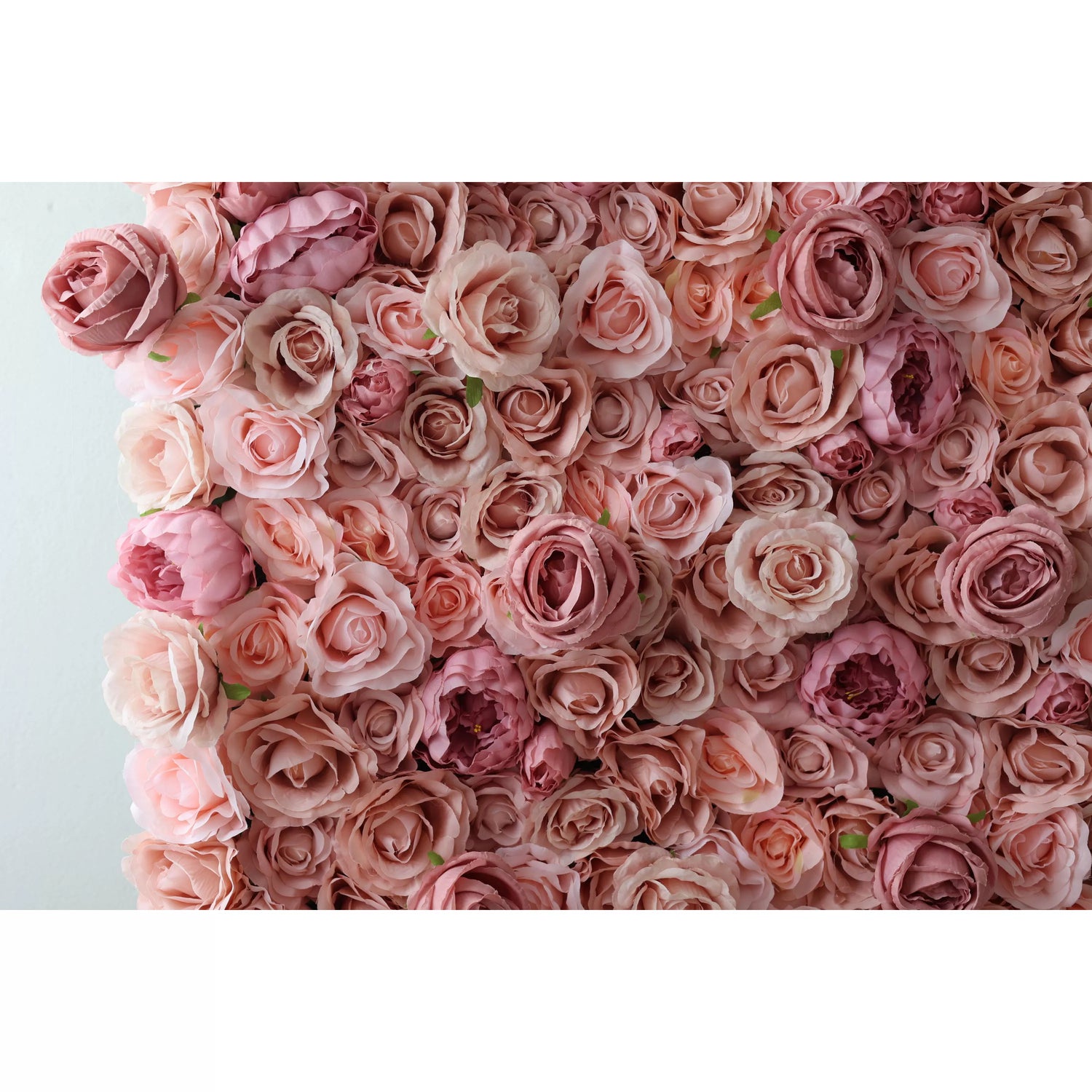A close - up of a lush artificial flower wall showcases an abundance of roses in soft pink and muted peach tones. The densely packed blooms, with their delicate petals and varied shades, create a romantic, dreamy texture. Green leaves peek through, adding a natural touch. Perfect for elegant decor, this floral arrangement exudes sweetness and sophistication, ideal for backdrops at weddings or events.