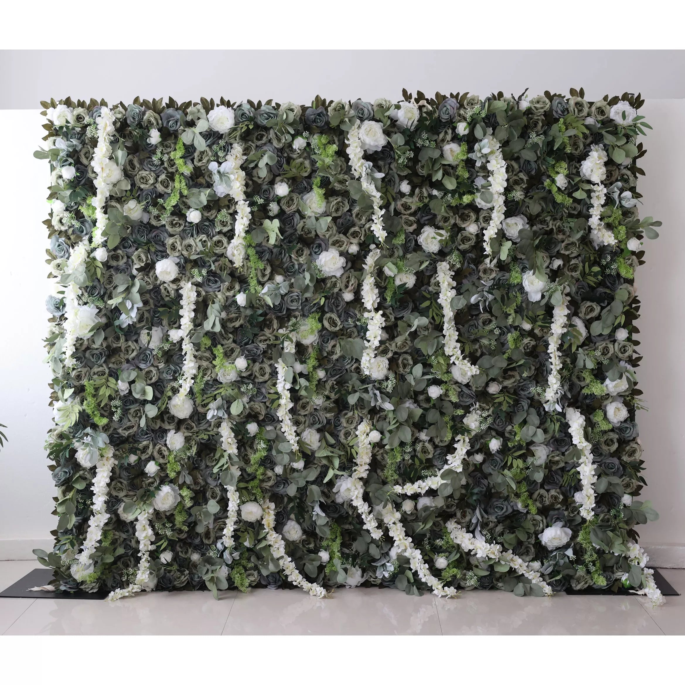 This large artificial greenery wall features a dense mix of dark green foliage, white roses, and trailing white flowers. A blue circle stands out in the center, adding a unique focal point. The lush, layered arrangement creates a natural - looking, elegant backdrop, perfect for events or decor.