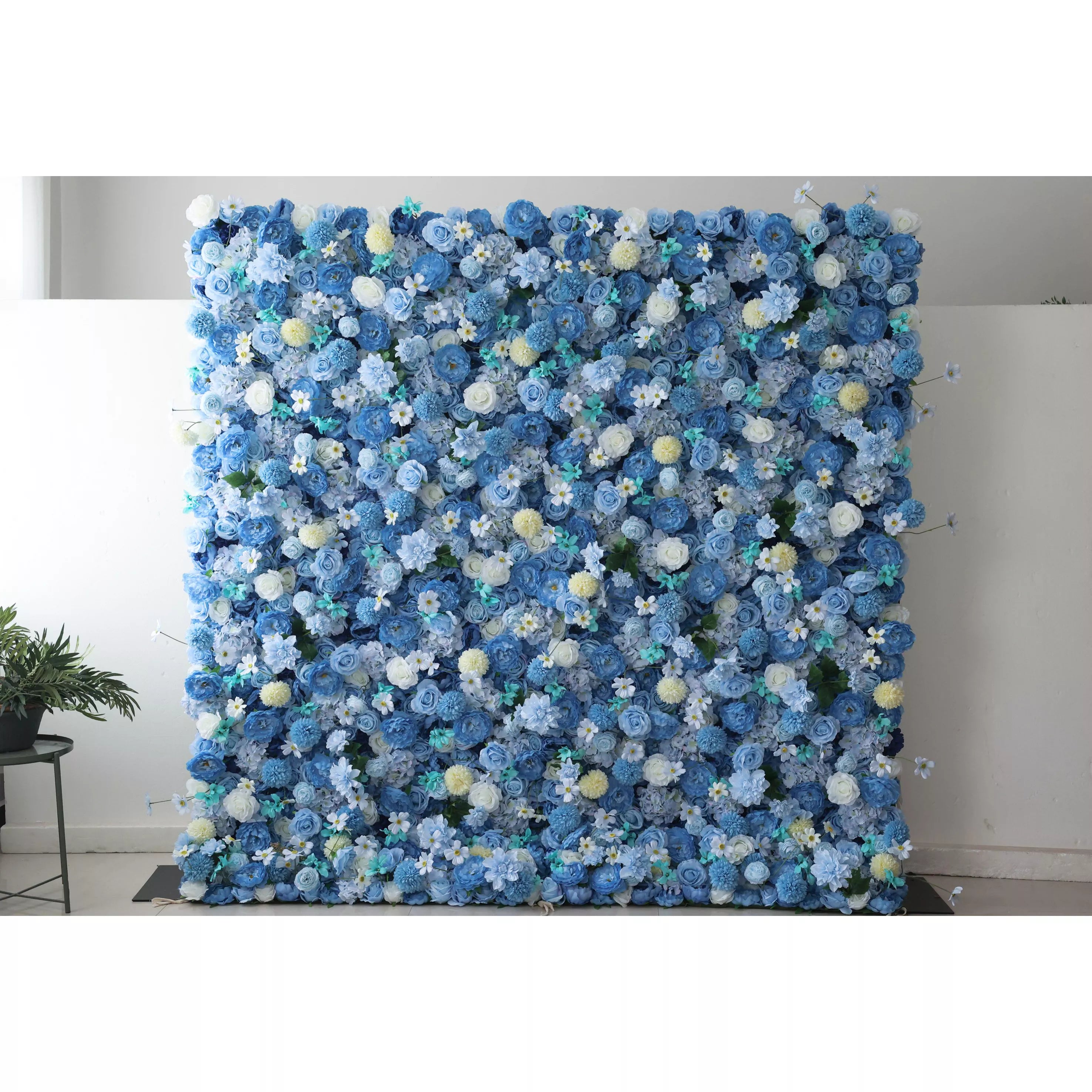 A large artificial flower wall features a lush arrangement of blue blooms, including roses, hydrangeas, and small white flowers. Accents of yellow pom - pom - like flowers and green foliage add texture. The harmonious blend of colors creates a vibrant, elegant backdrop, perfect for events or decorative spaces, exuding a sense of freshness and beauty.