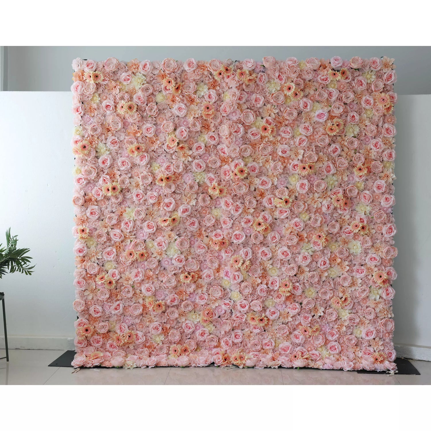 This picture features a large artificial flower wall, a beautiful blend of soft pink and peach tones. It’s densely packed with various blooms, including roses and daisy - like flowers, creating a lush, romantic display. The uniform arrangement and pastel colors make it perfect for event backdrops, adding an elegant and charming touch to any space, ideal for weddings or parties.