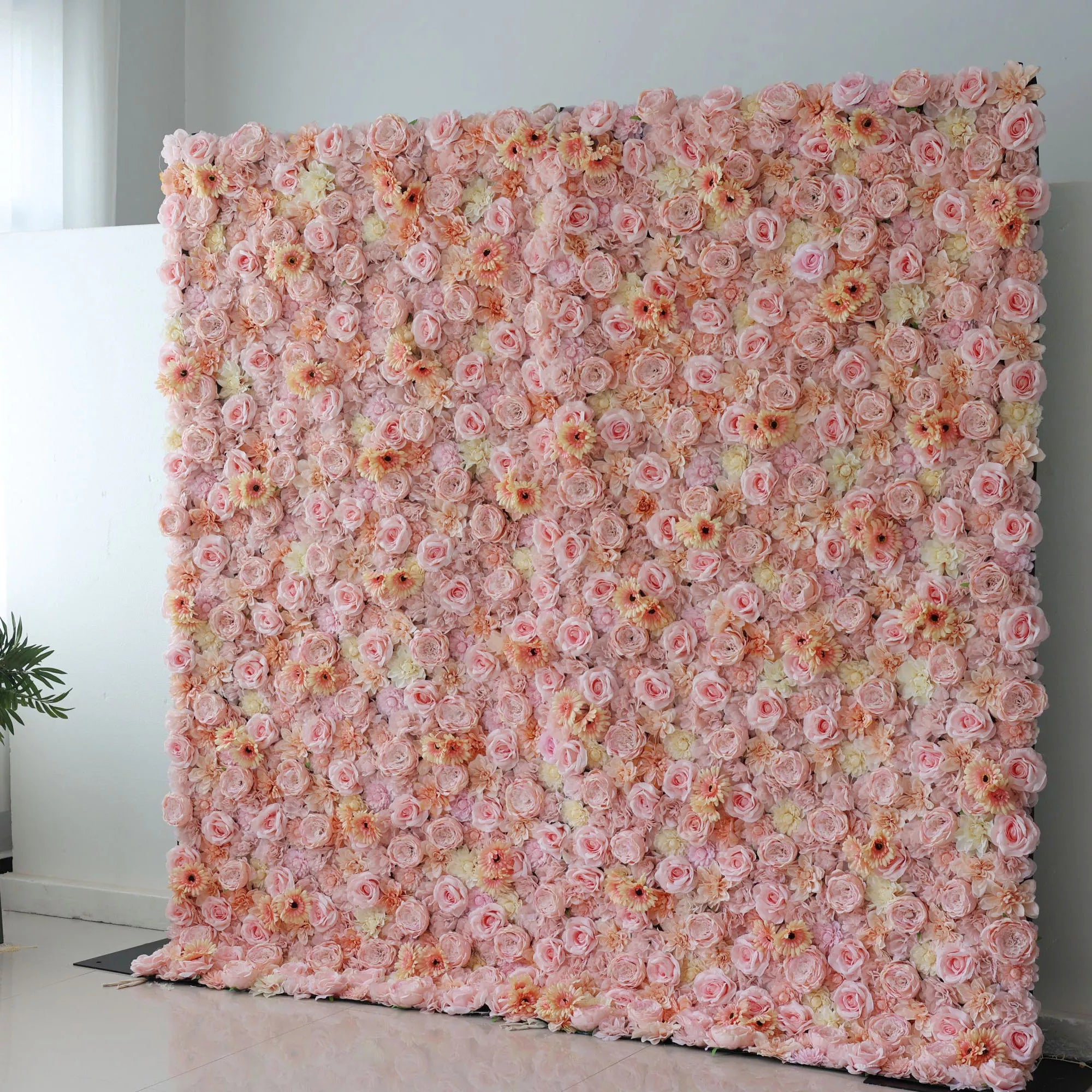 This picture showcases a large artificial flower wall, a beautiful blend of soft pink, peach, and cream tones. It’s densely packed with an array of blooms, including roses and daisy - like flowers, creating a lush, romantic display. The varied textures and pastel colors make it perfect for event backdrops, adding an elegant and charming touch to any space, ideal for weddings or parties to create a dreamy atmosphere.