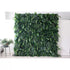 This picture presents a large, lush artificial greenery wall. It features a dense arrangement of diverse green leaves, including broad palm - like fronds and smaller, variegated foliage. The rich, verdant texture creates a natural, tropical - inspired backdrop. Placed against a plain white wall and floor, with a small plant visible on the side, it brings an instant touch of nature indoors, ideal for decorative uses in events or interior spaces.