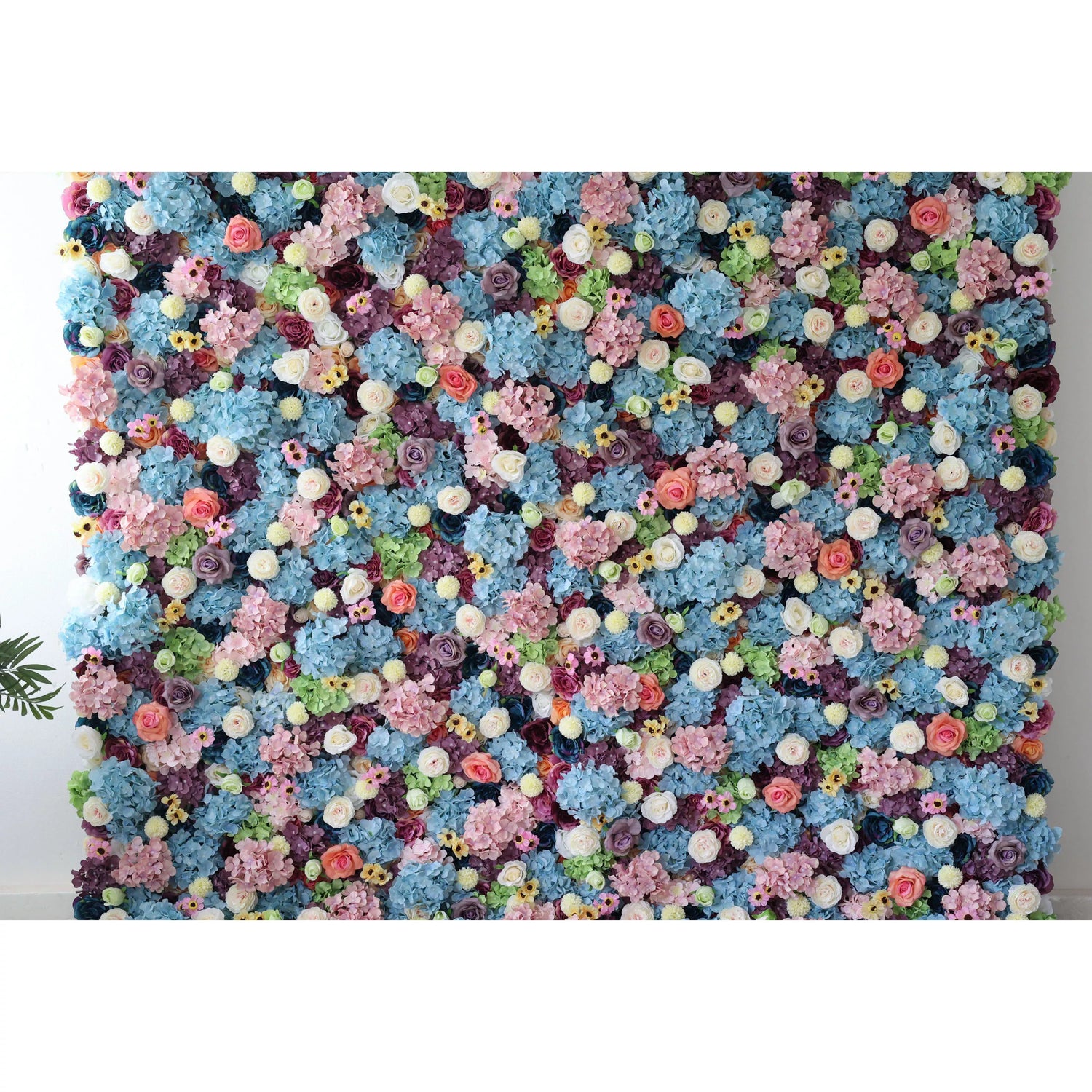 This is a large, vibrant artificial flower wall. It features a dense mix of blue hydrangeas, white roses, pink blossoms, yellow flowers, and green foliage. The colorful, lush arrangement creates a lively, eye - catching display, perfect for event backdrops, adding a cheerful and decorative touch to any space.