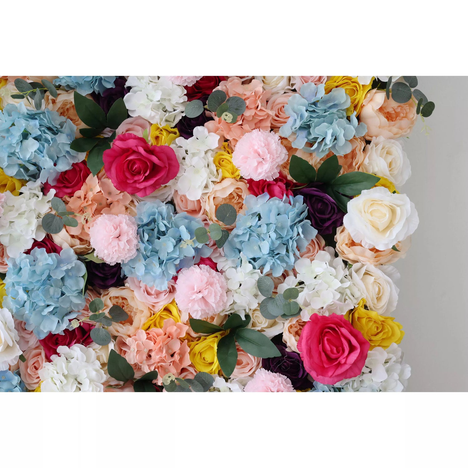 This is a vibrant artificial flower wall, densely packed with an array of colorful blooms. There are blue hydrangeas, red roses, white blossoms, along with soft - hued pink and peach flowers. Interspersed with green leaves, the wall creates a lively and eye - catching display. Ideal for event backdrops, it adds a cheerful and festive atmosphere to any occasion, such as weddings or parties.