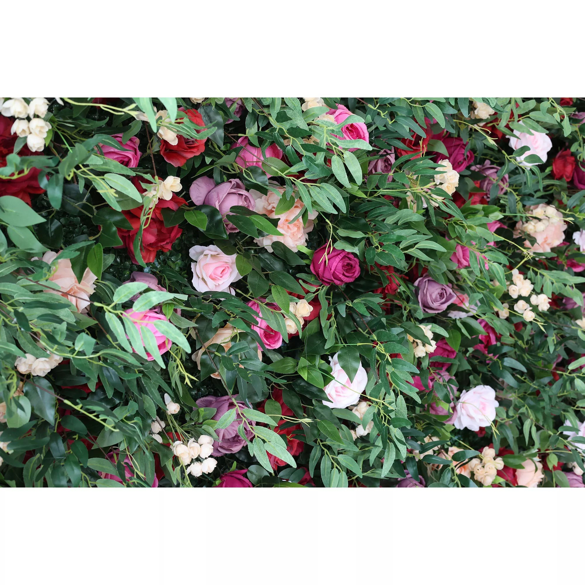 A close - up of an artificial flower wall features a vibrant mix of roses in pink, red, purple, and peach, interspersed with green foliage and small white blooms. The lush arrangement creates a romantic, decorative backdrop, ideal for events or adding a touch of elegance to a space.