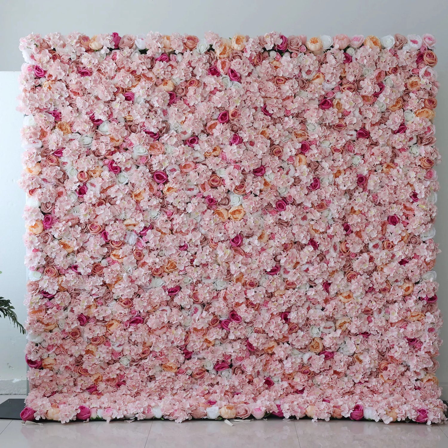 This flower wall is a lush, romantic display of artificial blooms. A soft pink base, dotted with peach - colored roses, deeper pink blossoms, and white flowers, creates a dreamy, textured pattern. The dense arrangement and gentle color palette make it perfect for weddings or elegant events, exuding charm and warmth.