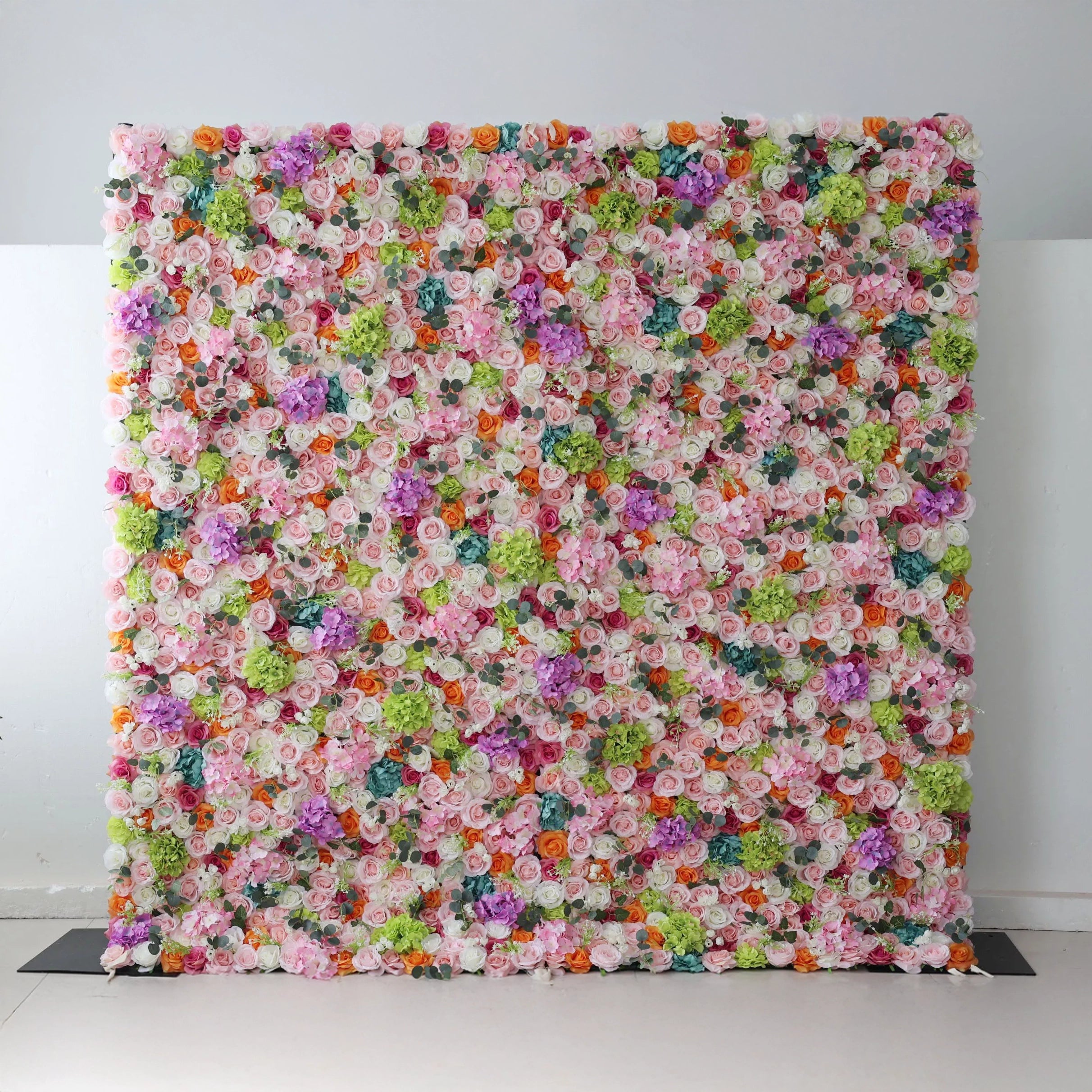 This flower wall is a vibrant, dense display of artificial blooms. A harmonious mix of colors—white, pink, purple, orange, and green—creates a lively, celebratory feel. Varied flower types and textures add depth, making it perfect for events like weddings or parties, exuding joy and elegance.