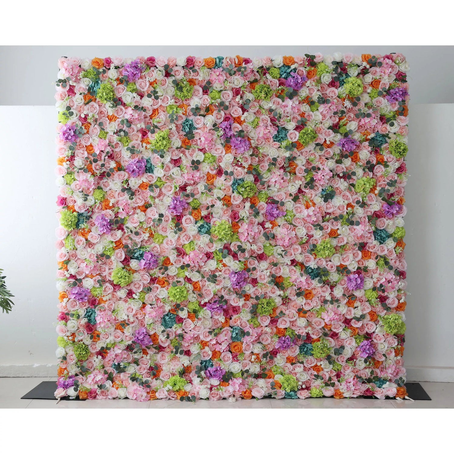 This flower wall is a vibrant, dense display of artificial blooms. A harmonious mix of colors—white, pink, purple, orange, and green—creates a lively, celebratory feel. Varied flower types and textures add depth, making it perfect for events like weddings or parties, exuding joy and elegance.