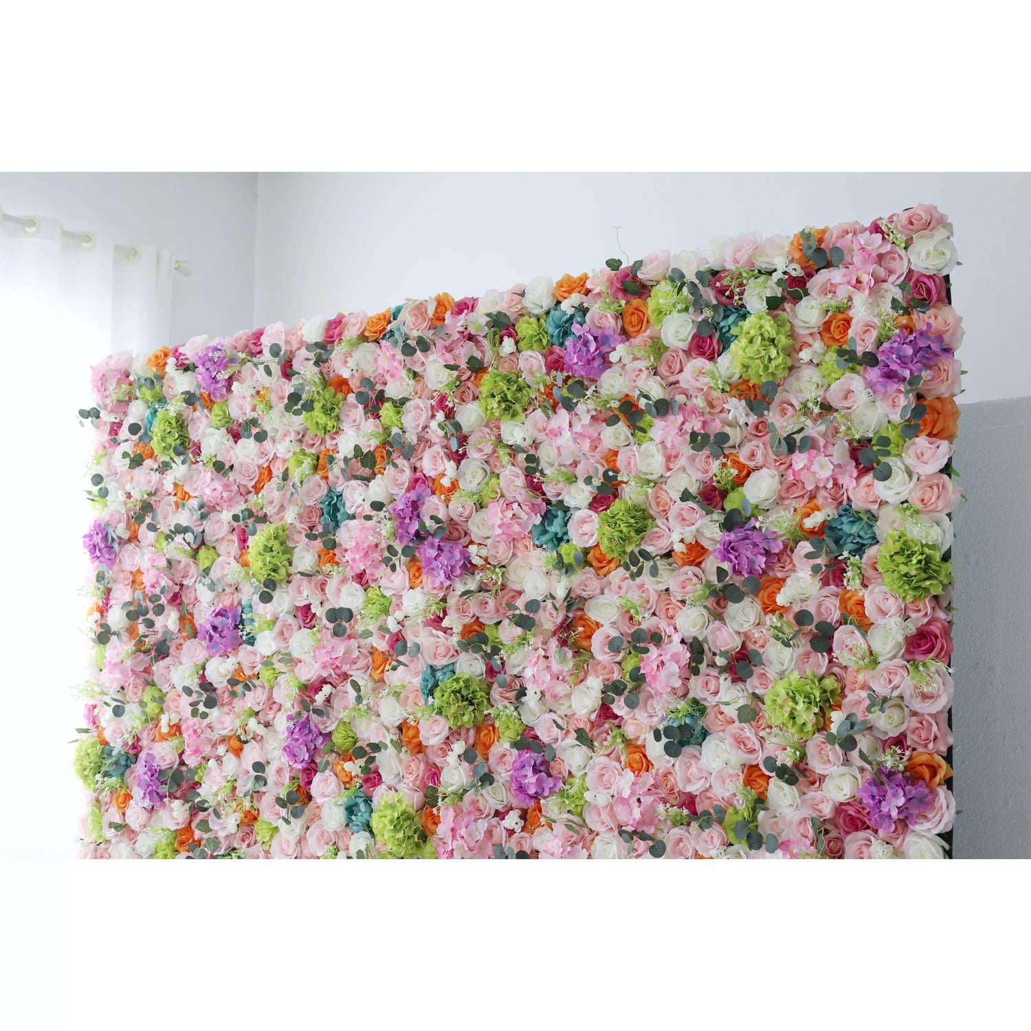 This flower wall is a lush and colorful display of artificial flowers. It features a diverse palette including shades of pink, white, orange, purple, and green, with roses and hydrangeas prominently interspersed. The dense arrangement, complemented by small eucalyptus - like leaves, creates a vibrant and lively atmosphere. Ideal for weddings, parties, or photo - shoots, it adds a touch of charm and a celebratory feel to any event.
